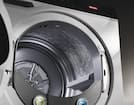 Close-up of a Miele front-load dryer interior, highlighting the honeycomb drum texture, lint filter, and open door for product detail.