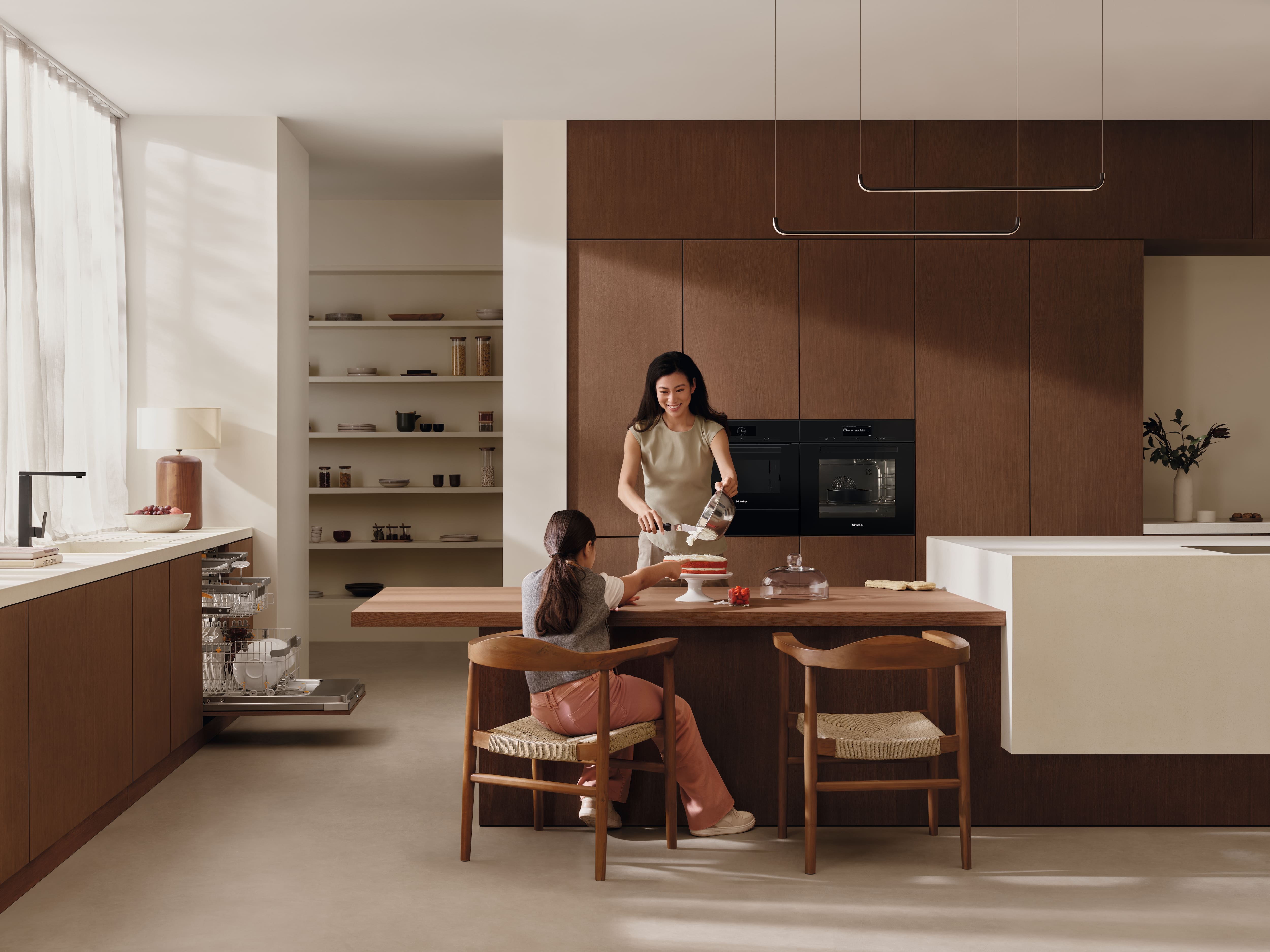 Woman and daughter baking in a modern kitchen with Miele appliances.