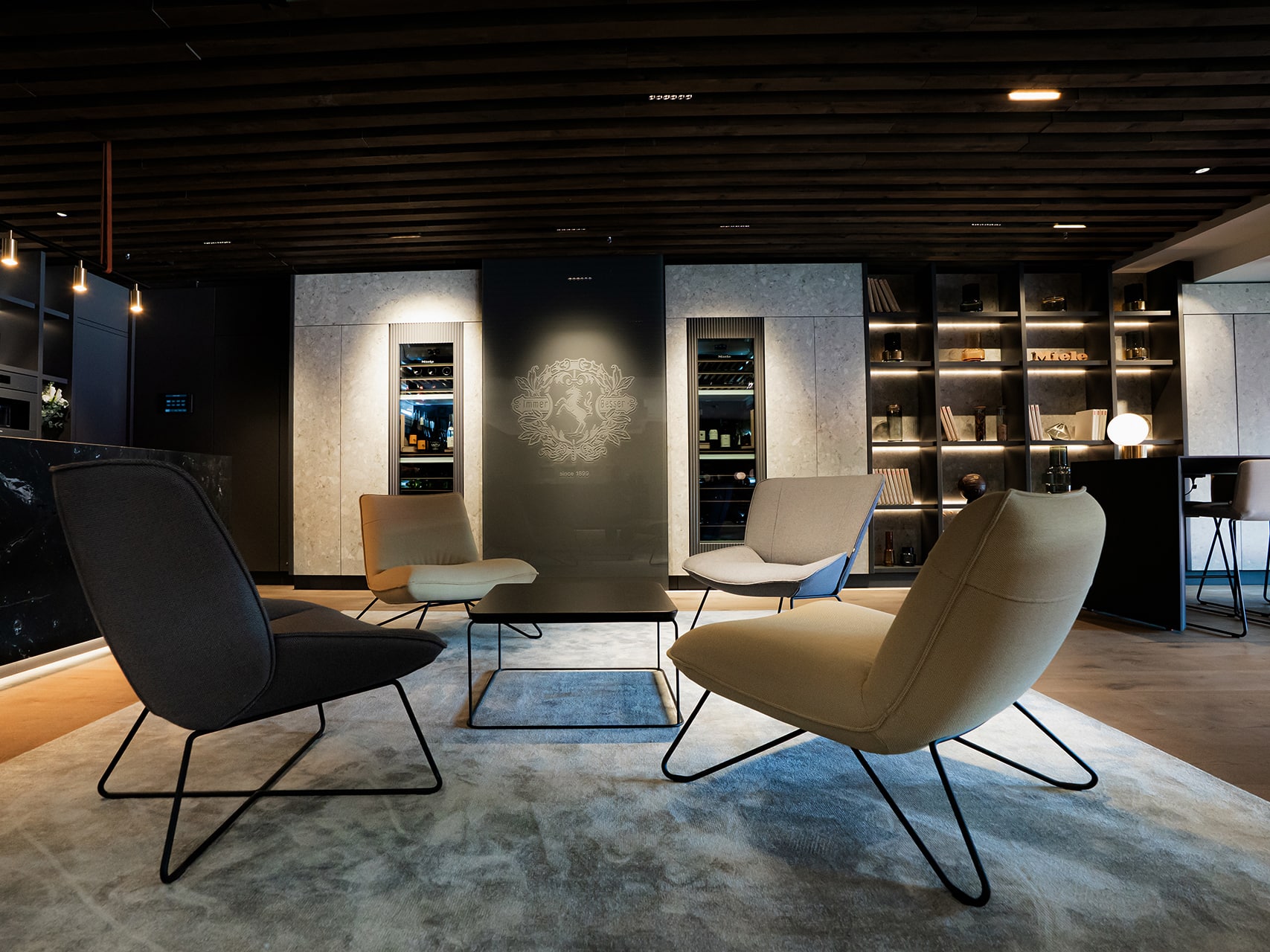 Moderne Lounge mit vier minimalistischen Sesseln um einen niedrigen Tisch, Holzlamellendecke, indirekt beleuchteten Regalen und stilvollem Barbereich. Das hochwertige Ambiente lädt zum Verweilen ein. Moderne Lounge mit vier minimalistischen Sesseln um einen niedrigen Tisch, Holzlamellendecke, indirekt beleuchteten Regalen und stilvollem Barbereich. Das hochwertige Ambiente lädt zum Verweilen ein.