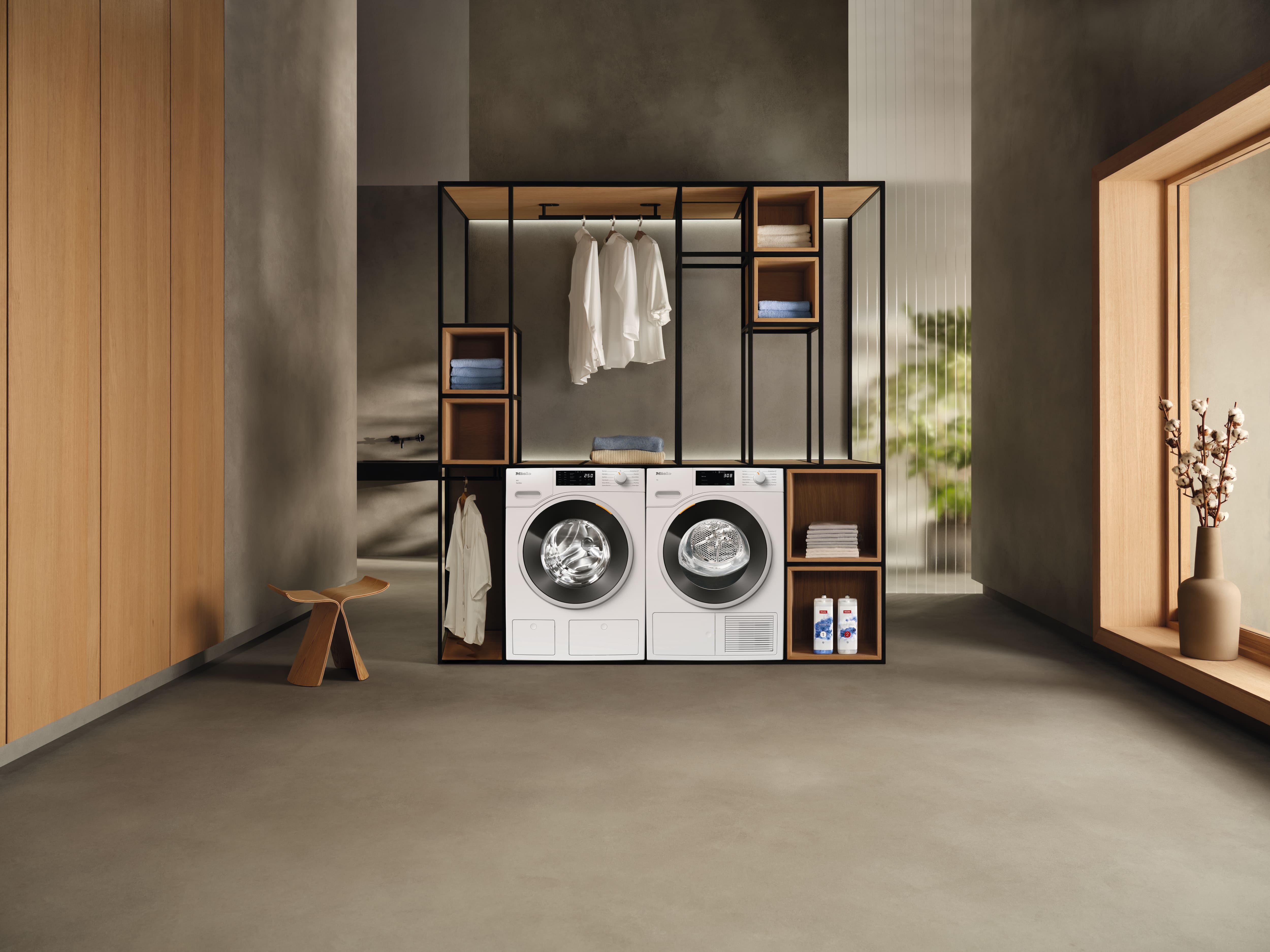 Minimalist laundry room with washer and dryer in open wood-metal shelving, hanging clothes, towels, detergents. Minimalist laundry room with washer and dryer in open wood-metal shelving, hanging clothes, towels, detergents.