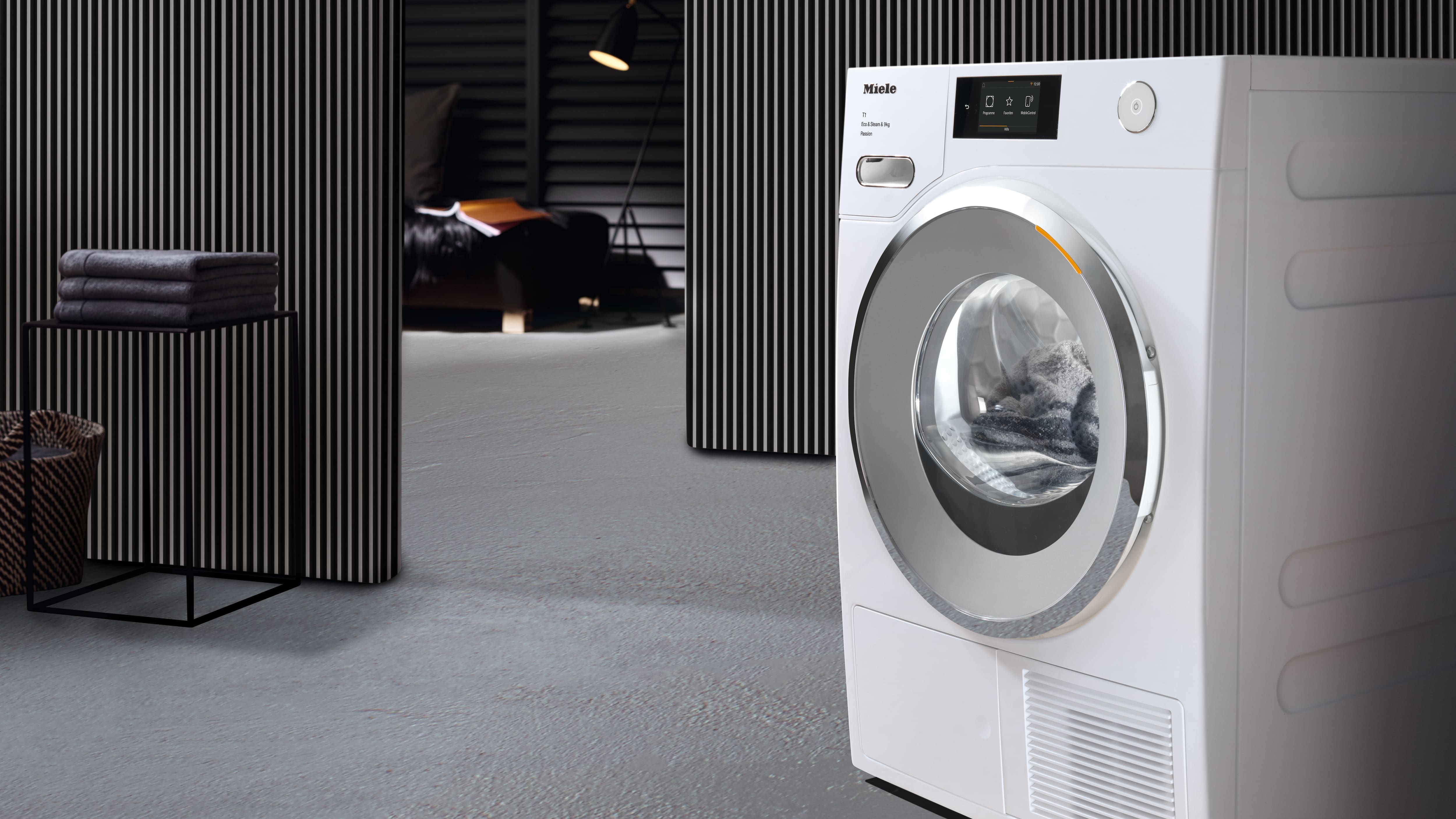 Tumble dryer in nice room with clothes hanging nearby on left side Tumble dryer in nice room with clothes hanging nearby on left side