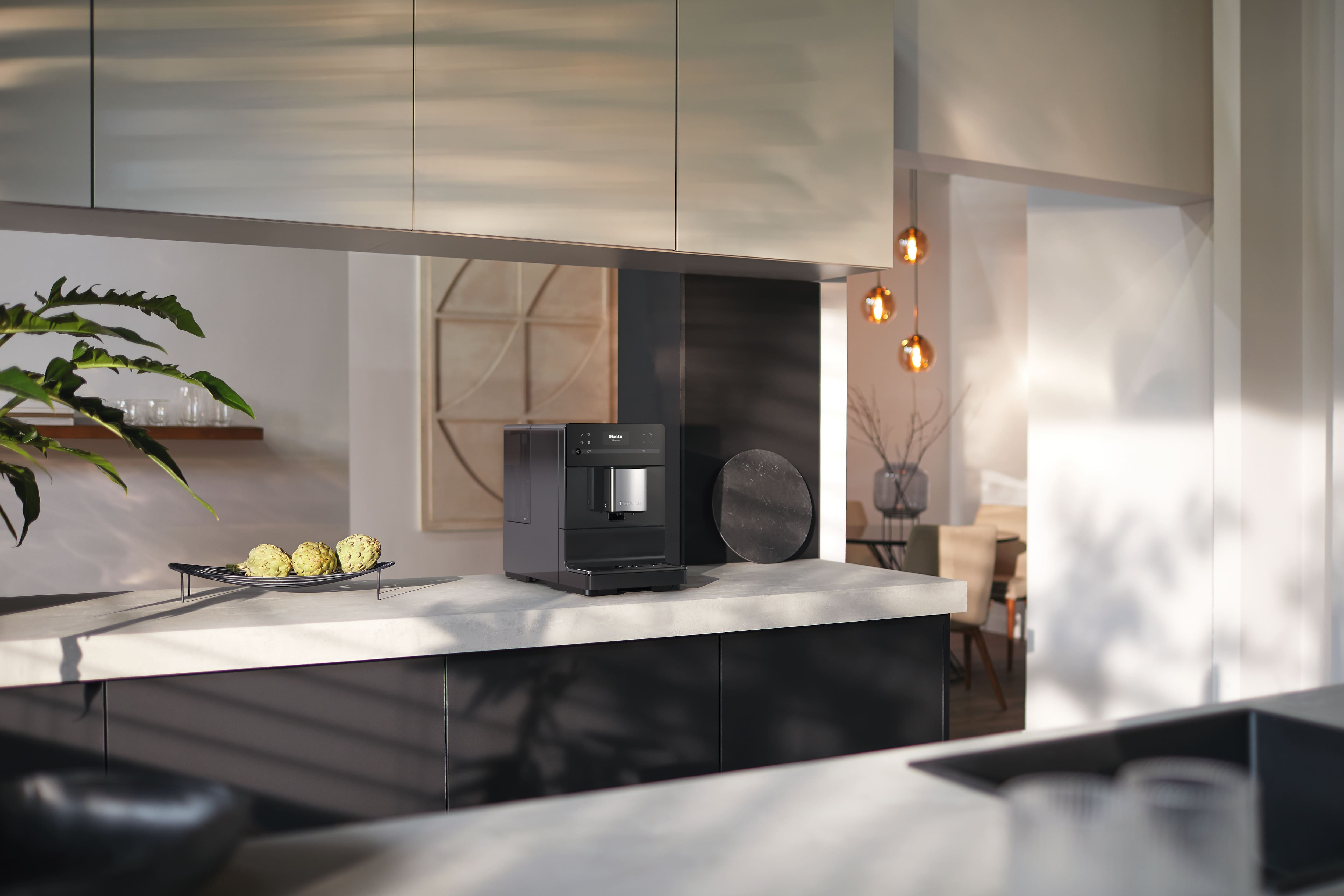 Miele Kaffeevollautomat auf einer modernen Kücheninsel in einer hellen Wohnküche. Miele Kaffeevollautomat auf einer modernen Kücheninsel in einer hellen Wohnküche.