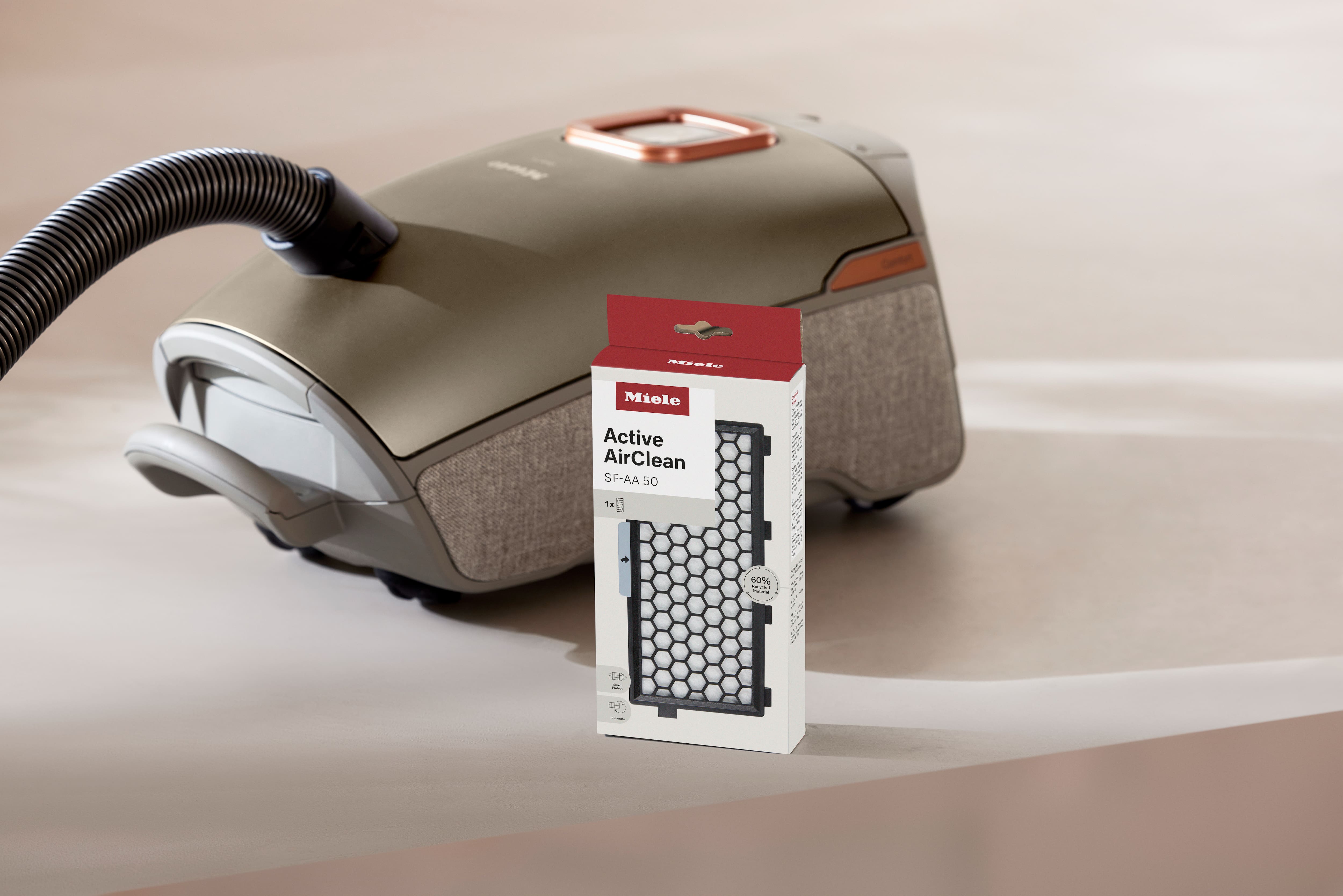 Box of Miele Active AirClean SF-AA 50 vacuum filter standing in front of a canister vacuum cleaner.