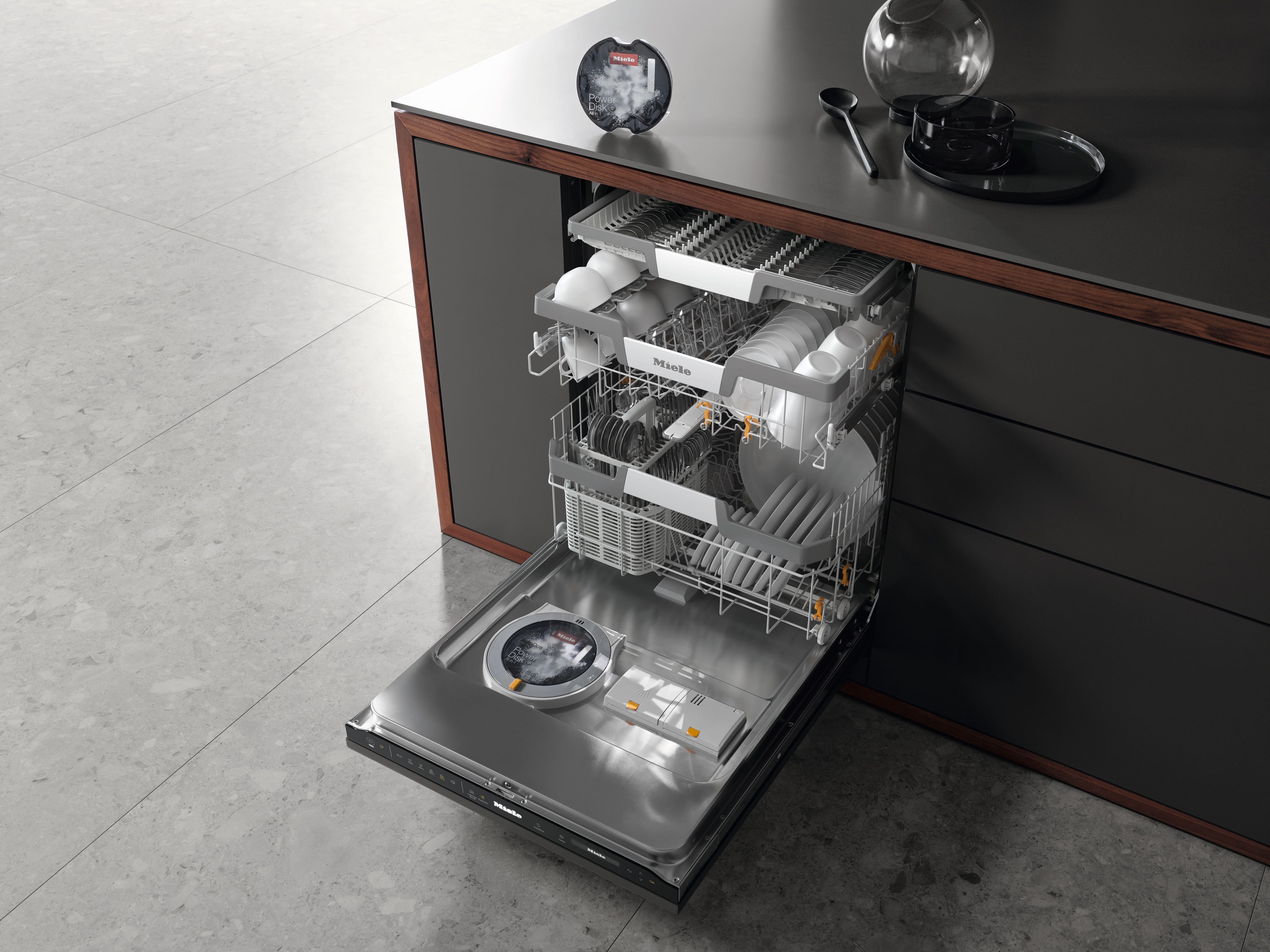 Open built-in dishwasher in a modern kitchen, racks filled with dishes and bowls, with sleek dark cabinetry. Open built-in dishwasher in a modern kitchen, racks filled with dishes and bowls, with sleek dark cabinetry.