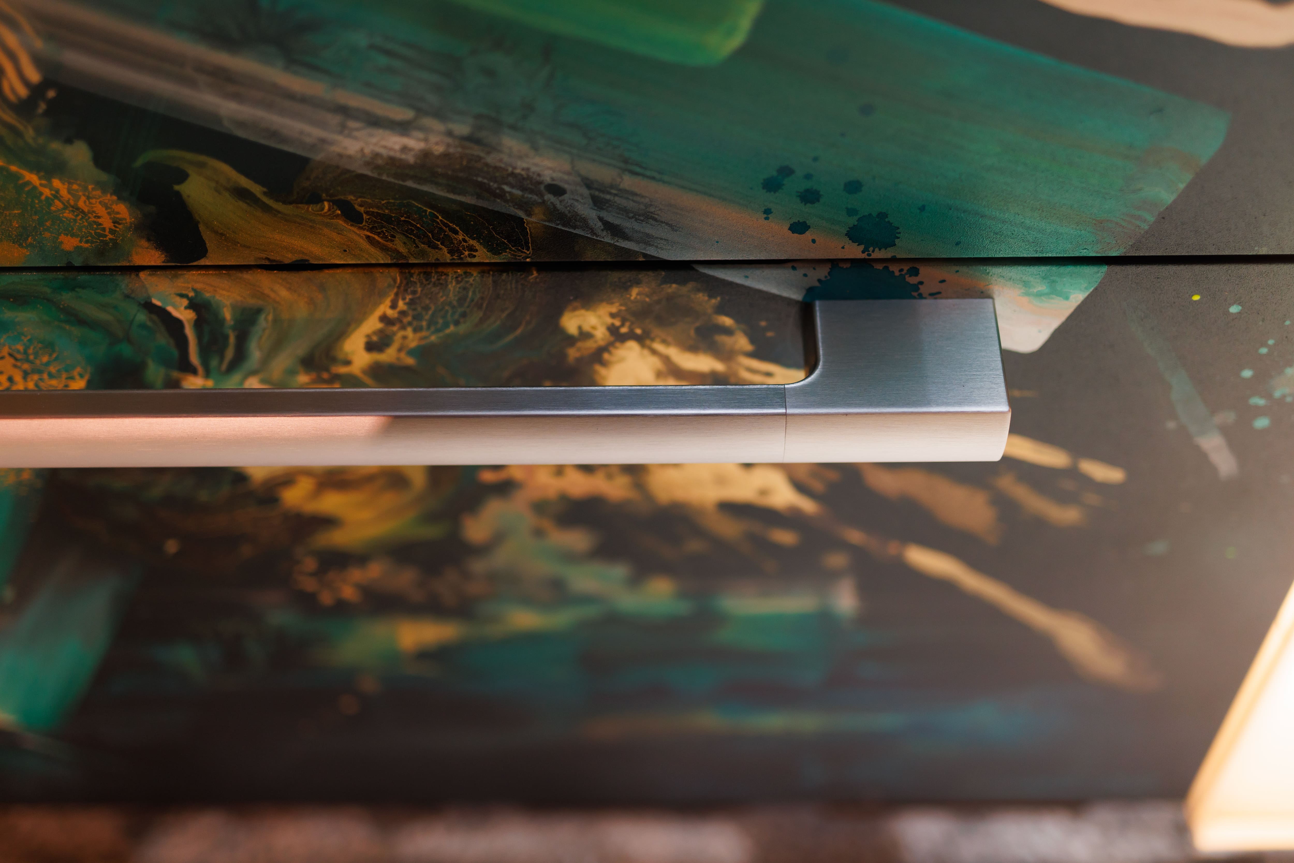 Detailed view of a Miele appliance with a custom art-wrapped panel in green, teal, and gold hues, showcasing the blend of contemporary art, premium design, and kitchen innovation featured in The Kitchen Muse. Detailed view of a Miele appliance with a custom art-wrapped panel in green, teal, and gold hues, showcasing the blend of contemporary art, premium design, and kitchen innovation featured in The Kitchen Muse.