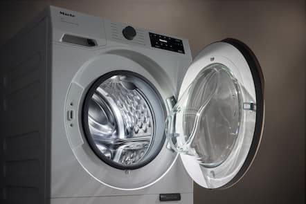Front-loading washing machine with door open, showing stainless steel drum and control panel; parts shown separately.