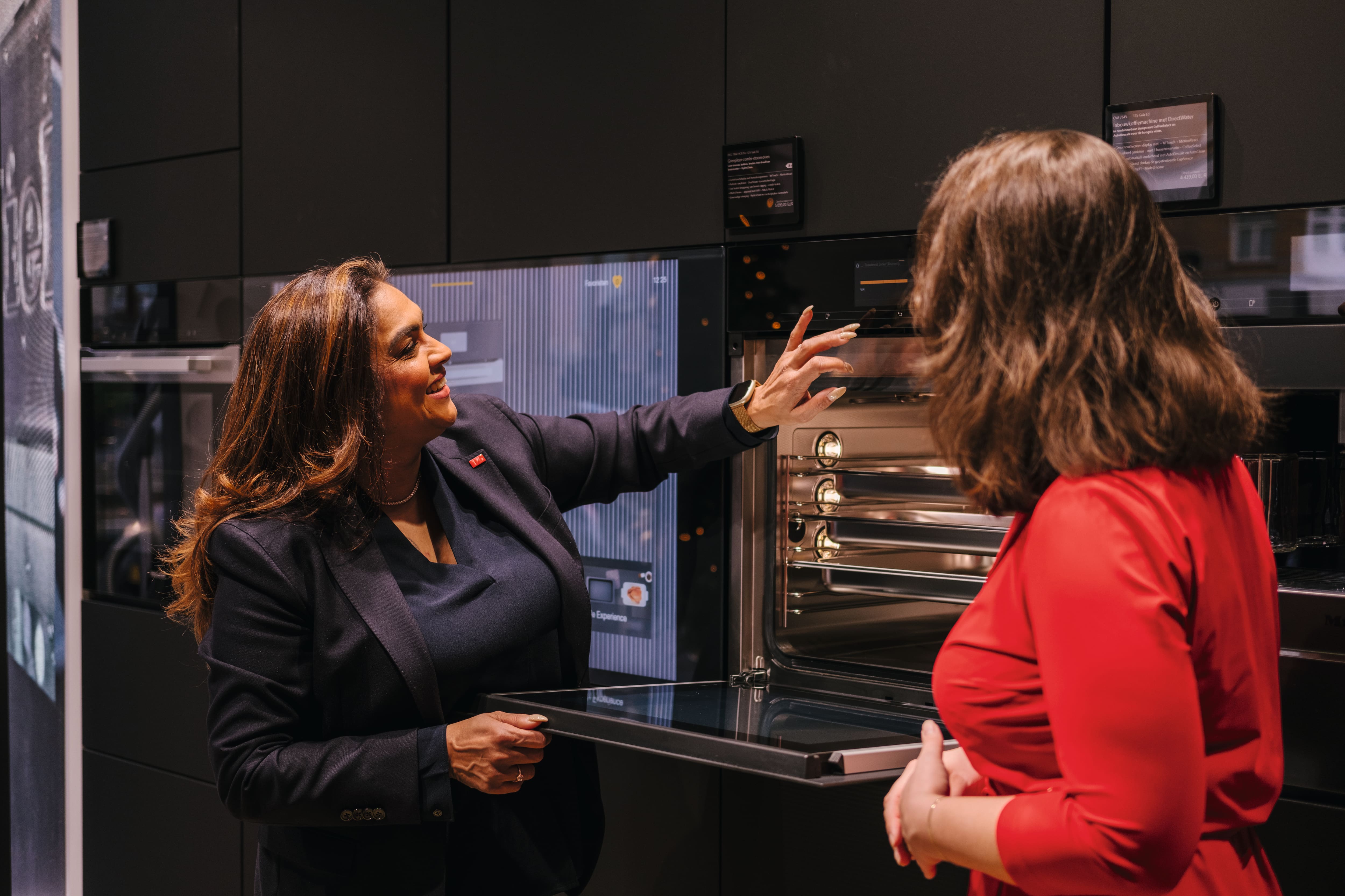 Servers in black uniforms offer a tray of wine and juice glasses to a guest at a modern reception. Servers in black uniforms offer a tray of wine and juice glasses to a guest at a modern reception.
