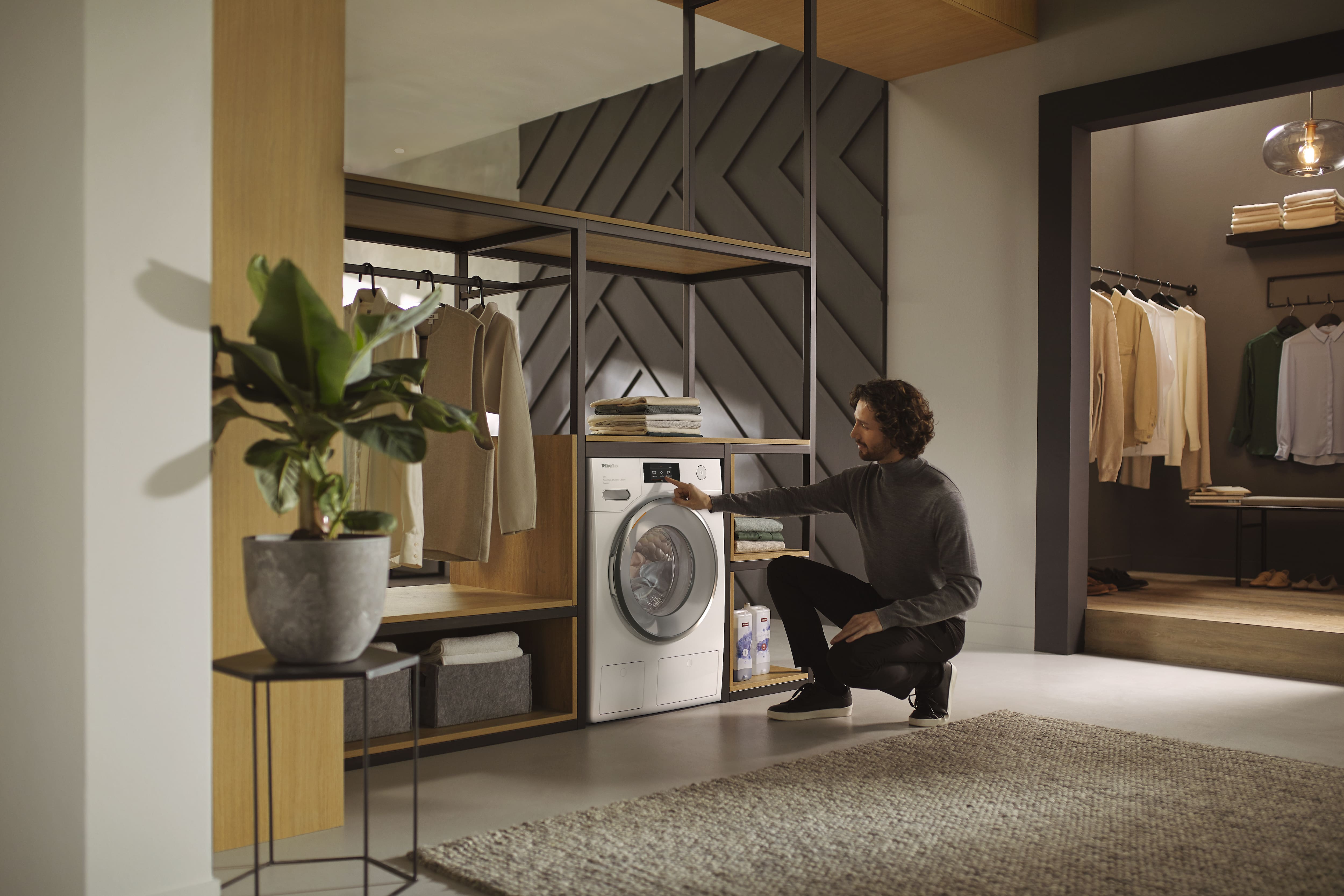 A person bent down loading a washing machine A person bent down loading a washing machine