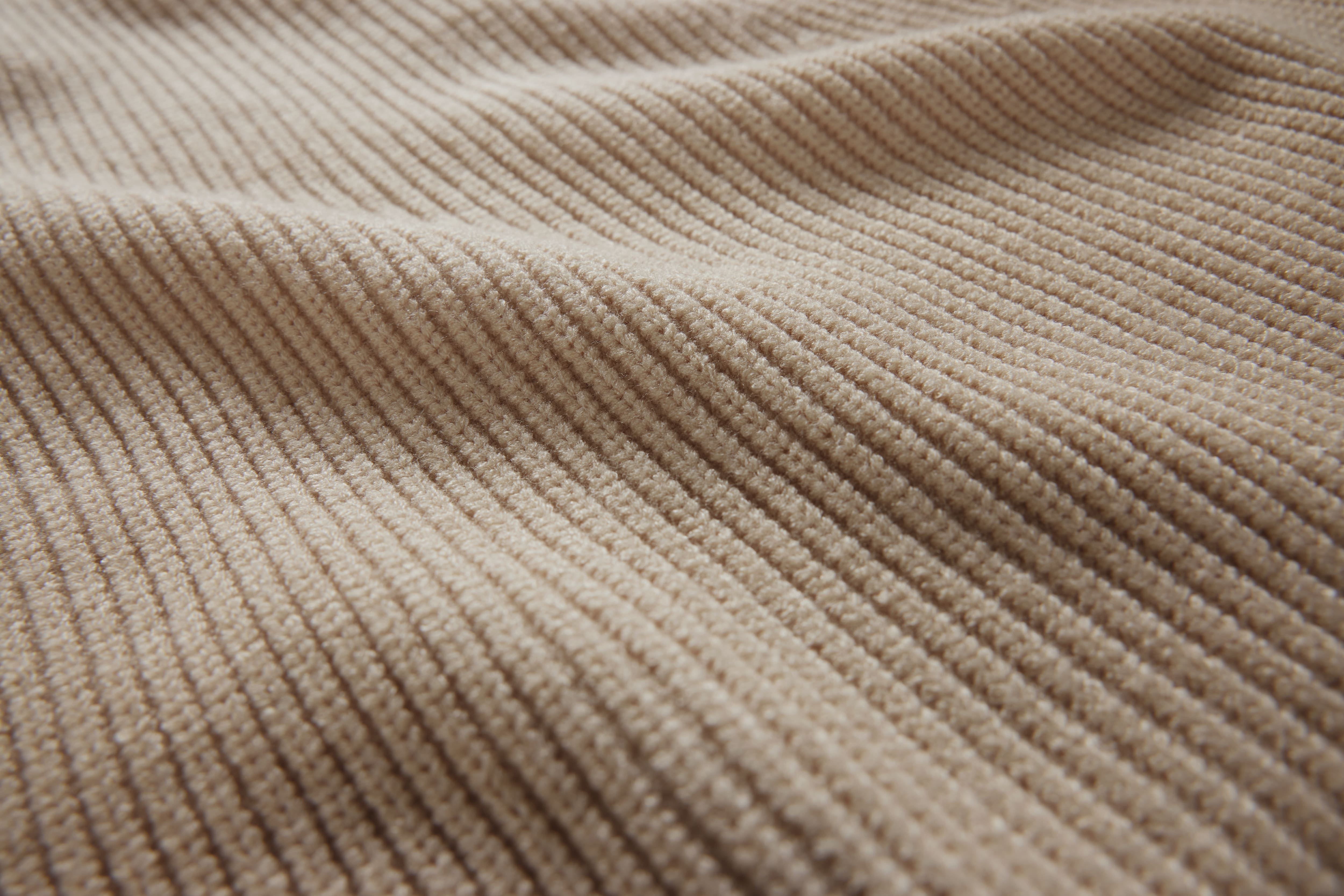 Primer plano de un tejido de punto acanalado de color beige con suaves ondulaciones, en el que se destacan la textura suave y los detalles, para su uso en el ámbito textil o del diseño. Primer plano de un tejido de punto acanalado de color beige con suaves ondulaciones, en el que se destacan la textura suave y los detalles, para su uso en el ámbito textil o del diseño.