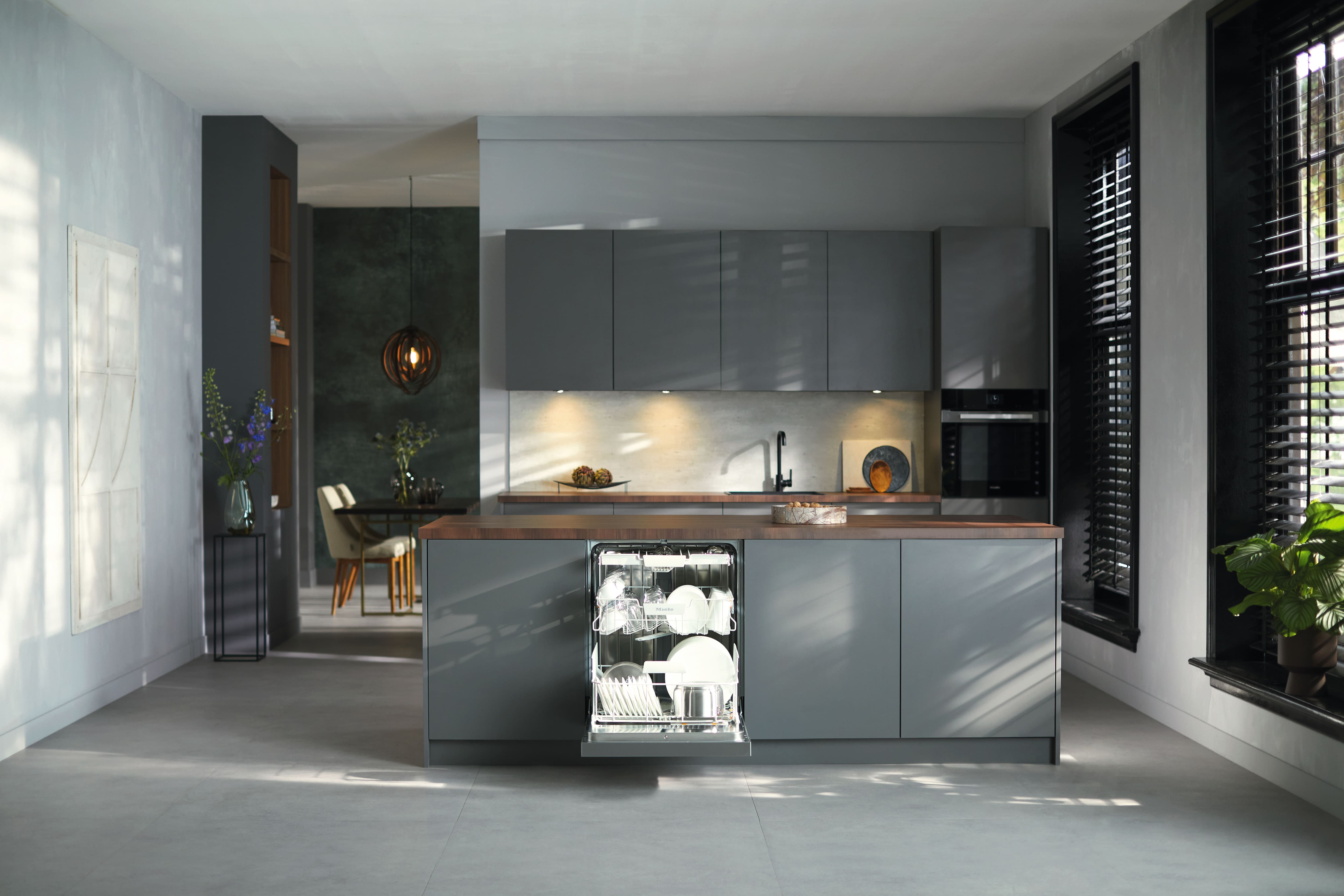Modern gray kitchen with island and open built-in dishwasher, showcasing sleek cabinetry and lighting. Modern gray kitchen with island and open built-in dishwasher, showcasing sleek cabinetry and lighting.