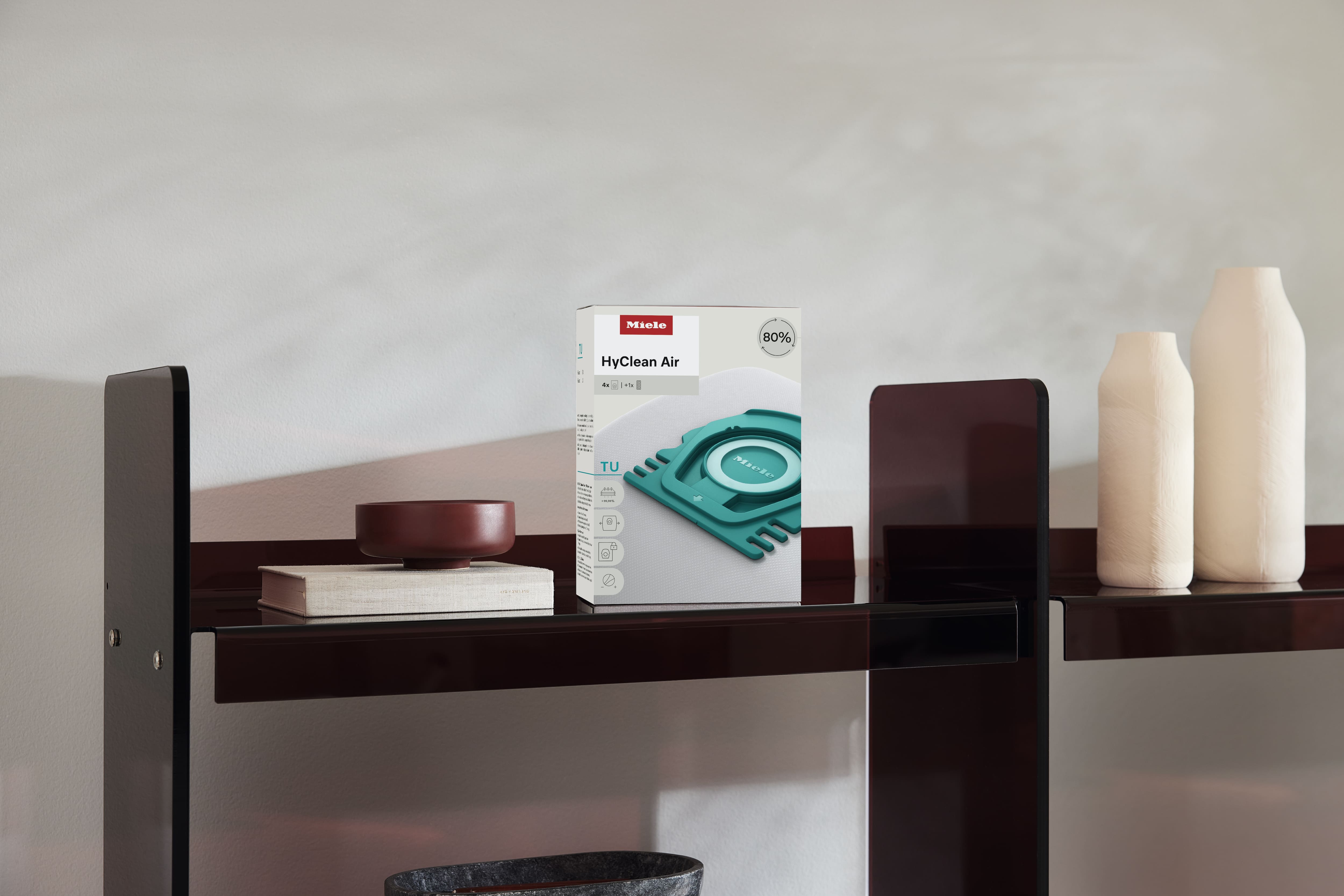 Box of Miele HyClean Air vacuum cleaner bags on a modern shelf beside minimalist vases and decor. Box of Miele HyClean Air vacuum cleaner bags on a modern shelf beside minimalist vases and decor.