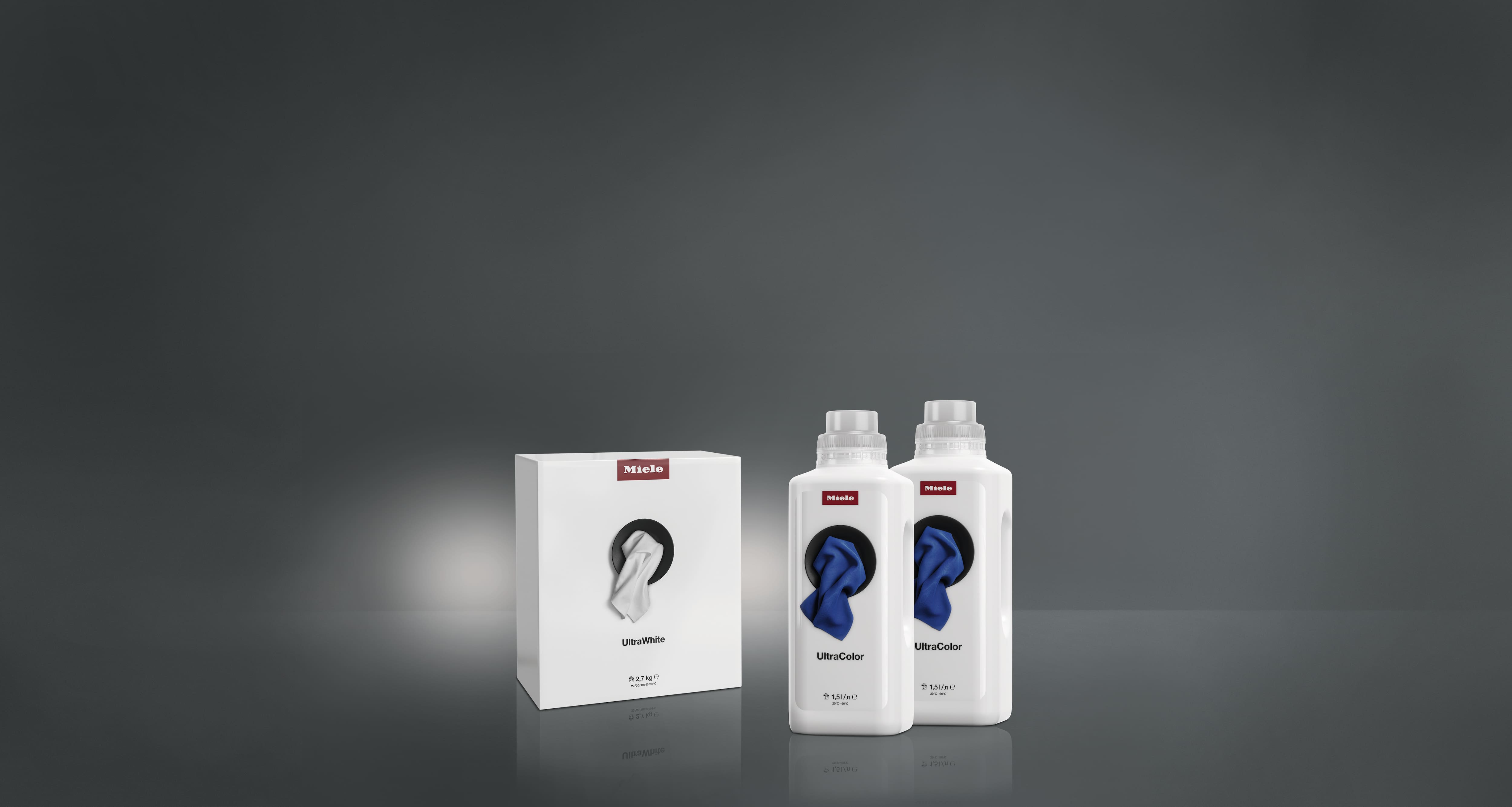 Product shot of Miele UltraWhite and UltraColor laundry detergents, boxes and bottles arranged on a gray studio background. Product shot of Miele UltraWhite and UltraColor laundry detergents, boxes and bottles arranged on a gray studio background.