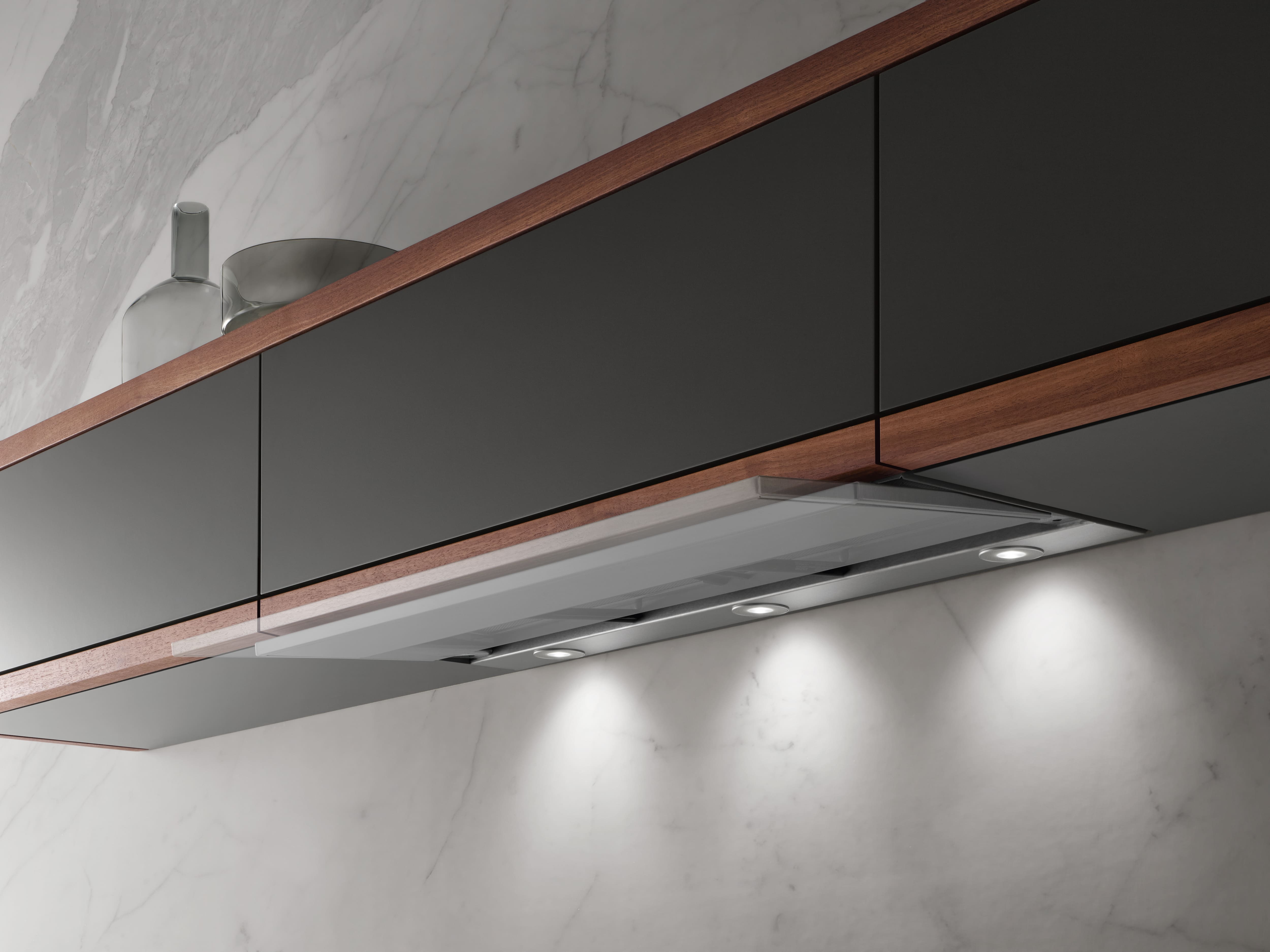 Ultra-slim under-cabinet kitchen range hood with built-in LED lights, integrated in dark wood cabinetry.