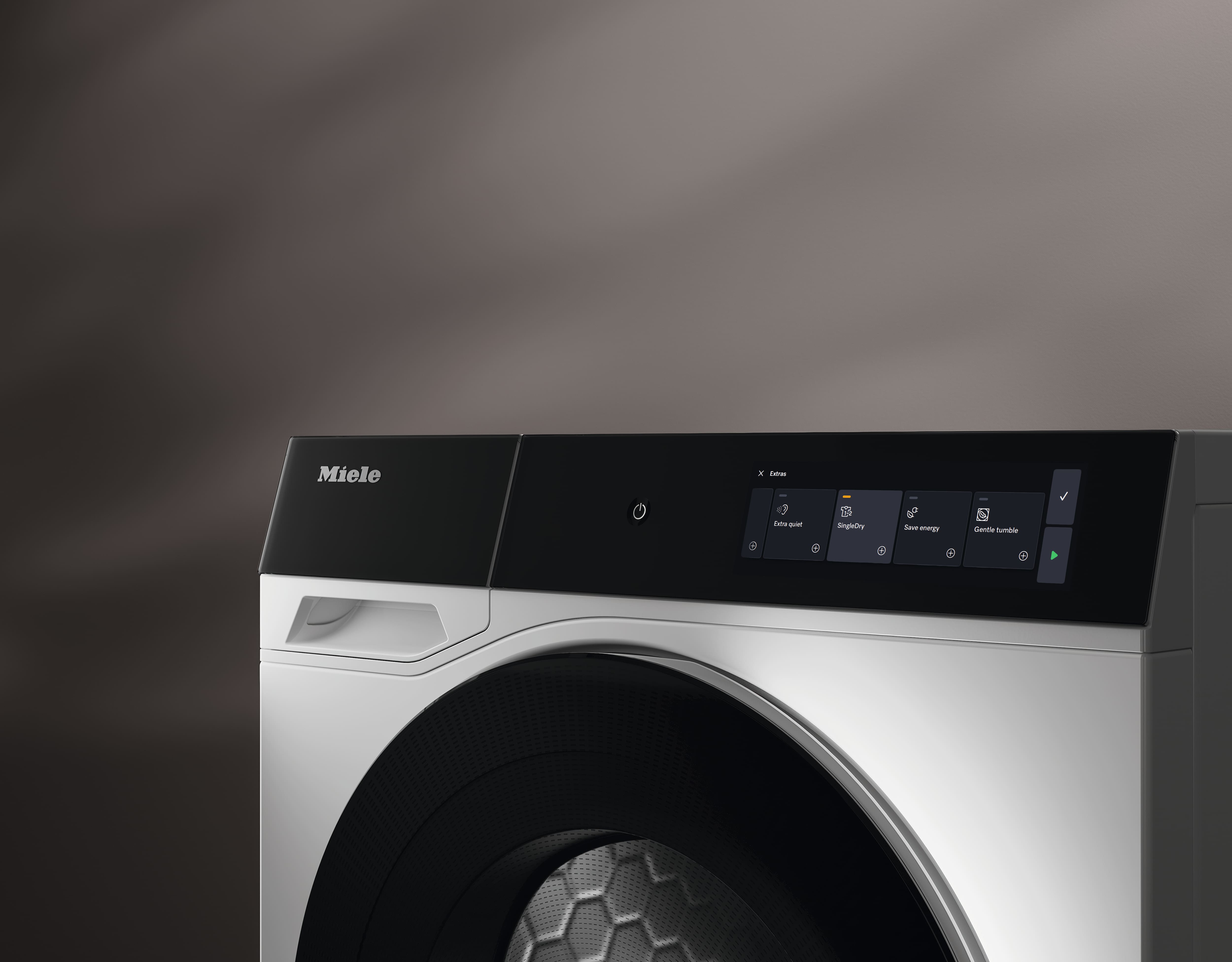 Nahaufnahme eines modernen Miele Trockners mit schwarzem Touch-Bedienfeld und grosser Trommeltür. Die Anzeige zeigt verschiedene Trockenprogramme und Einstellungen für eine komfortable und intuitive Bedienung.
