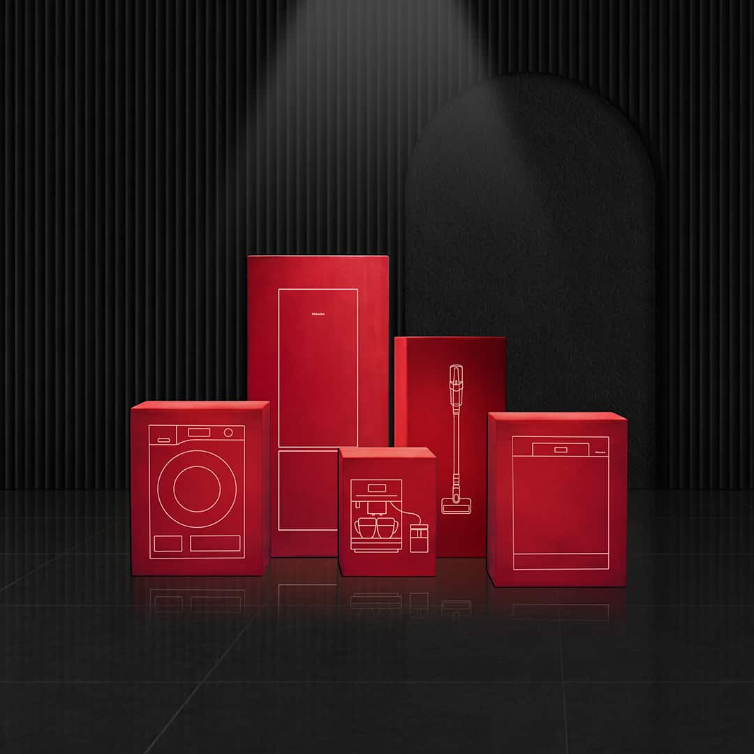 Red boxes with white line drawings of home appliances arranged under a spotlight in a dark, modern showroom setting. Red boxes with white line drawings of home appliances arranged under a spotlight in a dark, modern showroom setting.
