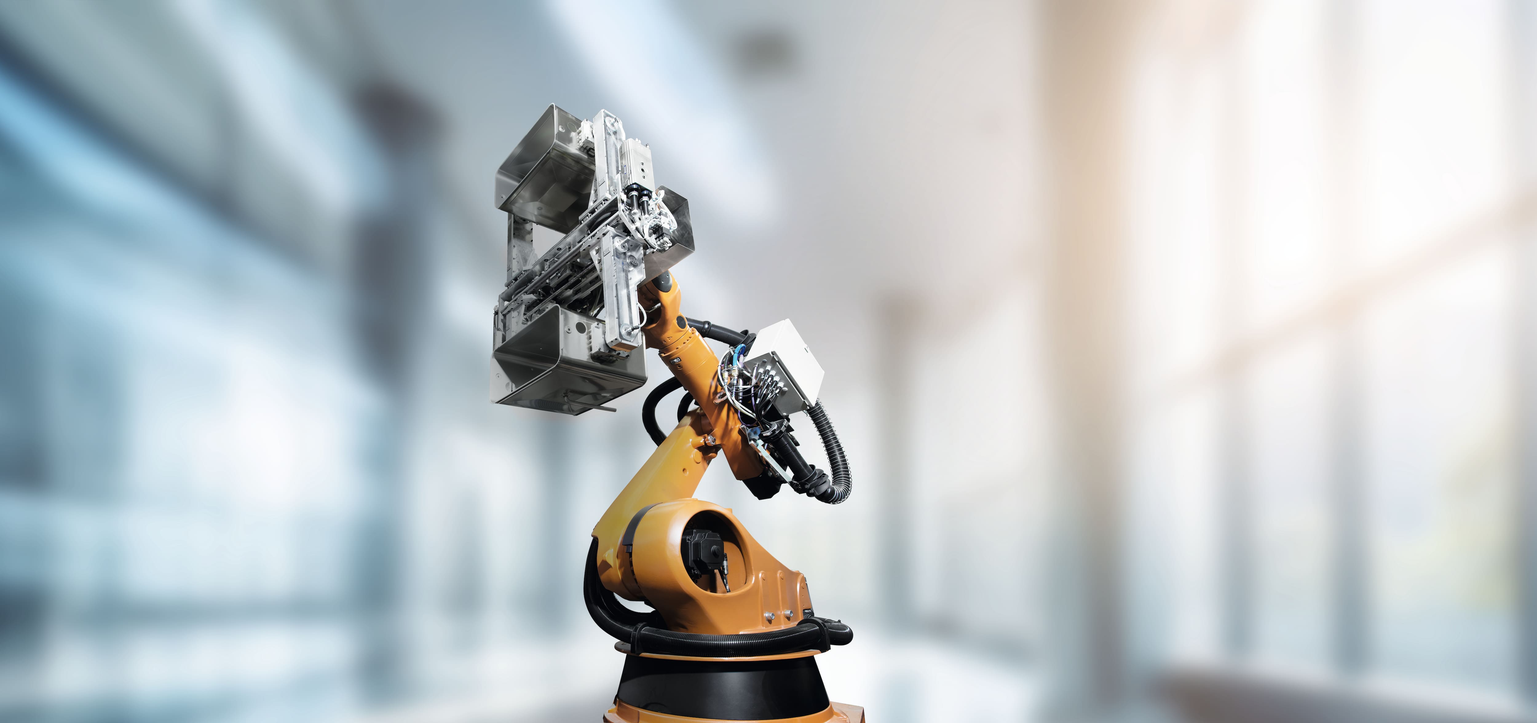 Orangefarbener Industrieroboter mit Greifarm arbeitet in einer hellen, modernen Produktionsumgebung. Die Szene steht für automatisierte Fertigung, Präzision und innovative Produktionstechnologien.