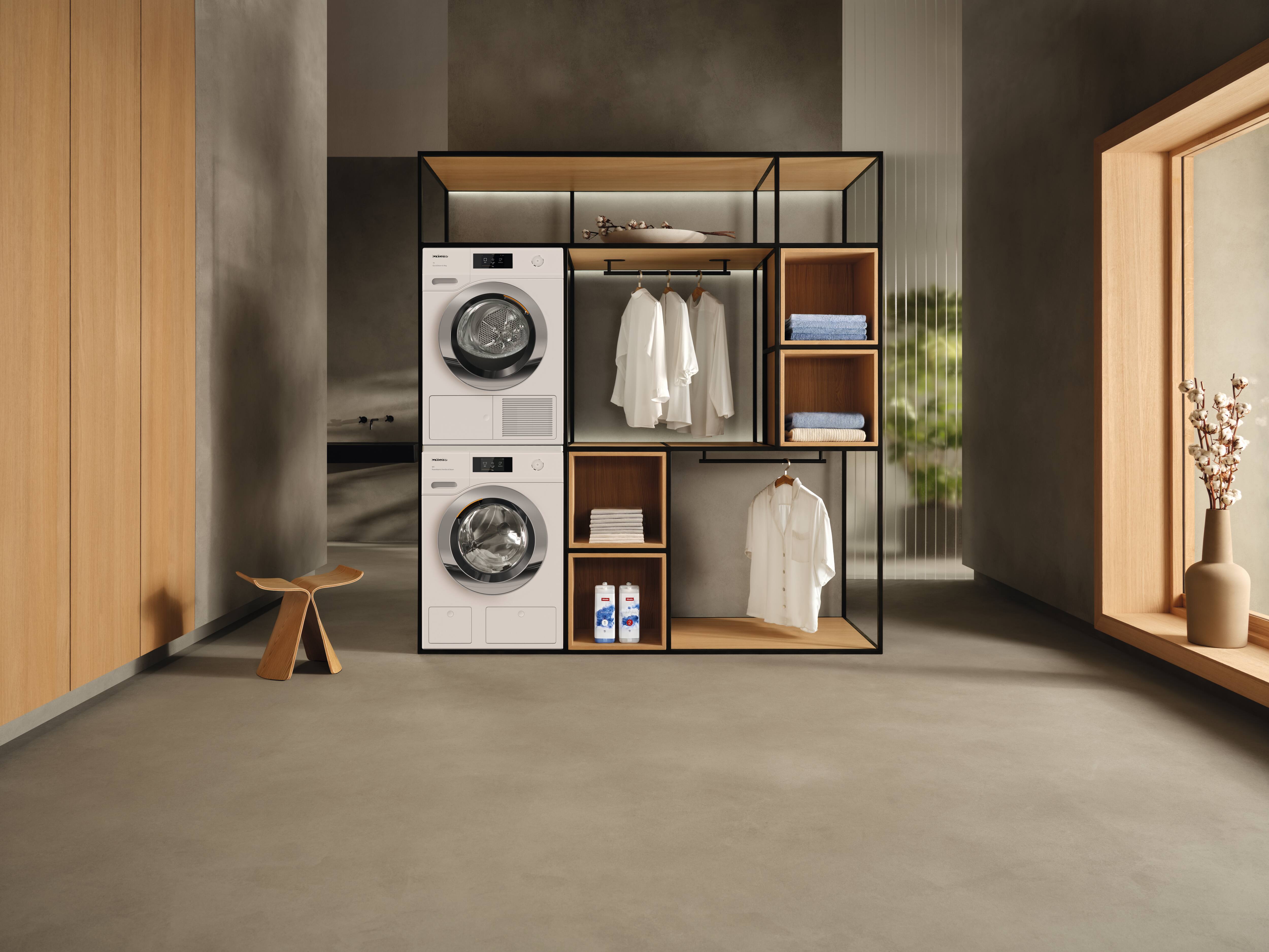 Nicho de lavanderia minimalista com lavadora e secadora empilhadas, prateleiras abertas, camisas brancas penduradas, toalhas e detergentes. Nicho de lavanderia minimalista com lavadora e secadora empilhadas, prateleiras abertas, camisas brancas penduradas, toalhas e detergentes.