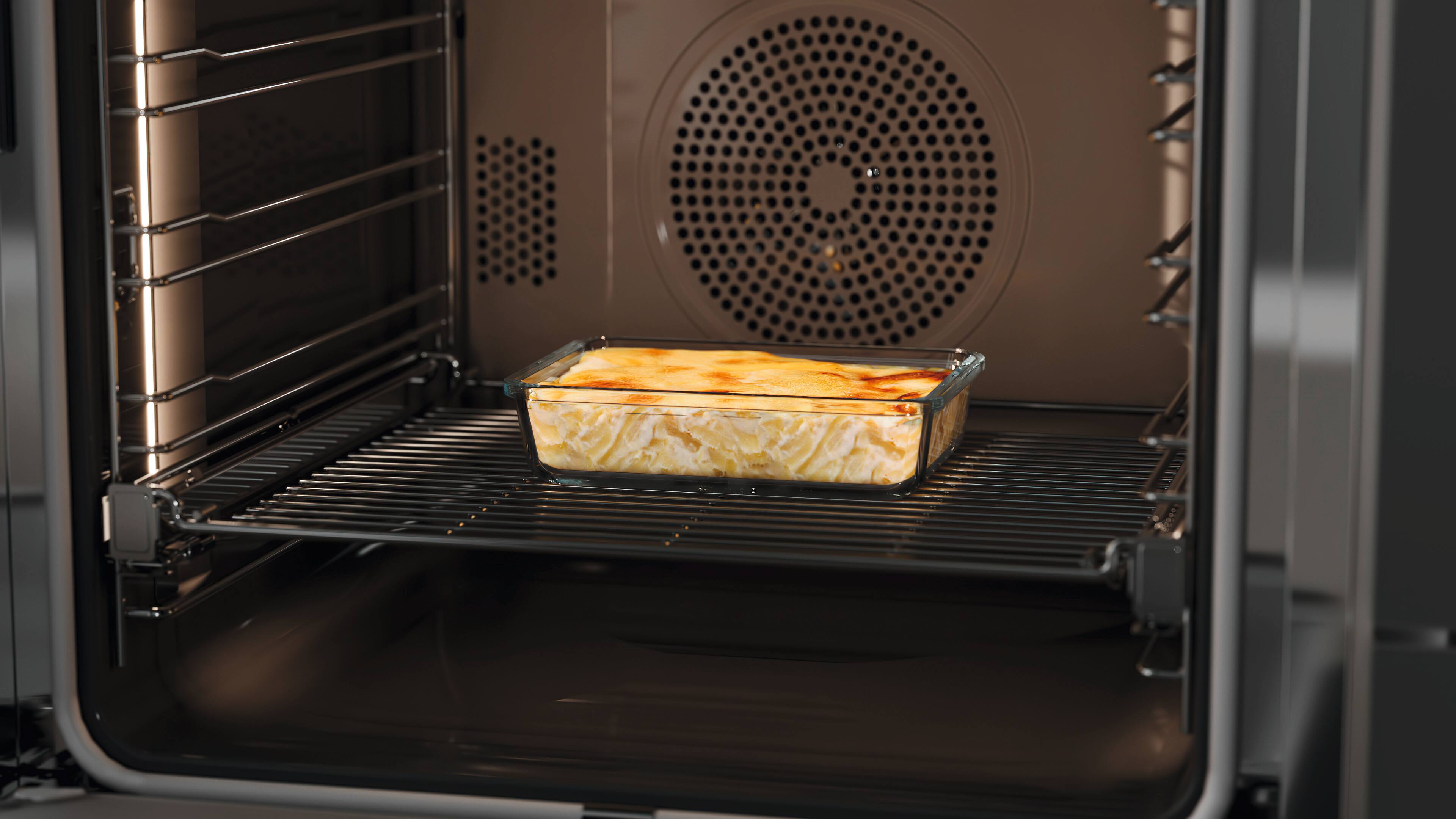Glass baking dish with a baked cheesy casserole sitting on the middle rack inside a modern convection oven. Glass baking dish with a baked cheesy casserole sitting on the middle rack inside a modern convection oven.