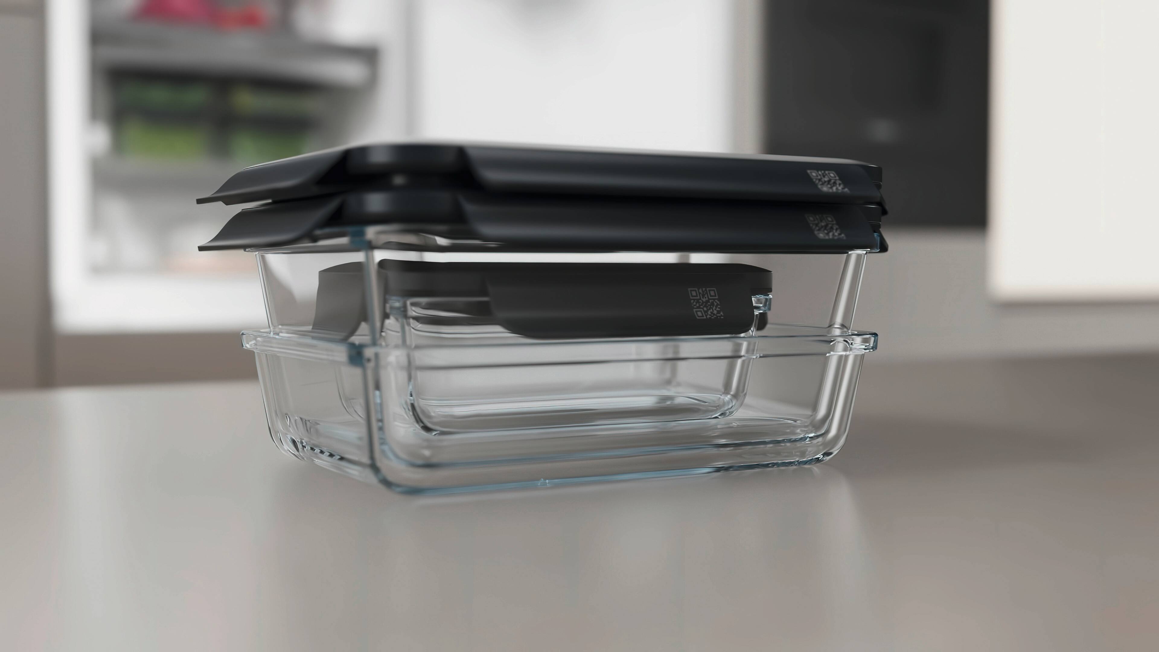 Three rectangular glass food storage containers with matte black lids, arranged diagonally on a light background. Three rectangular glass food storage containers with matte black lids, arranged diagonally on a light background.