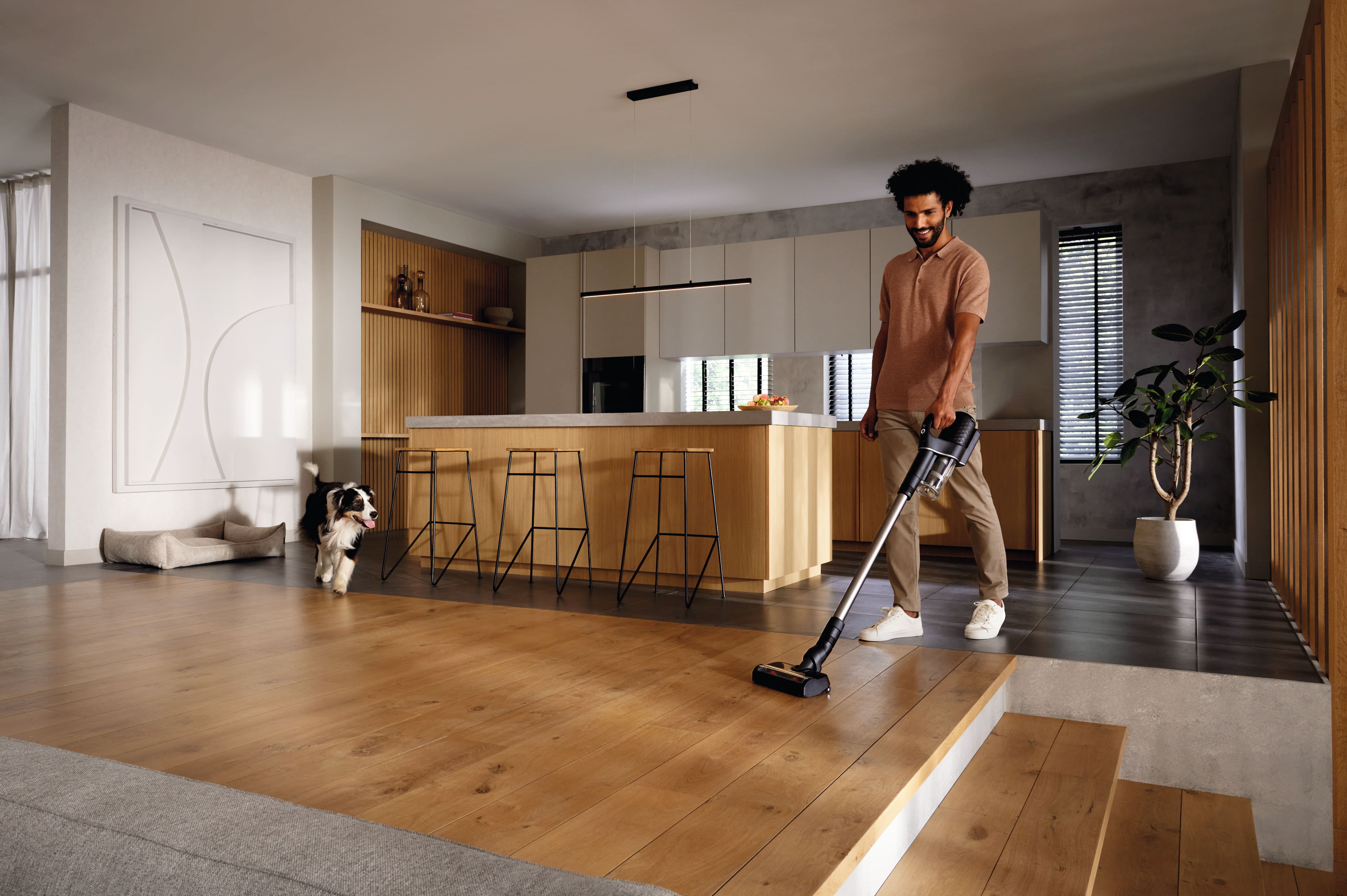 Modern kitchen interior with a person vacuuming hardwood floors