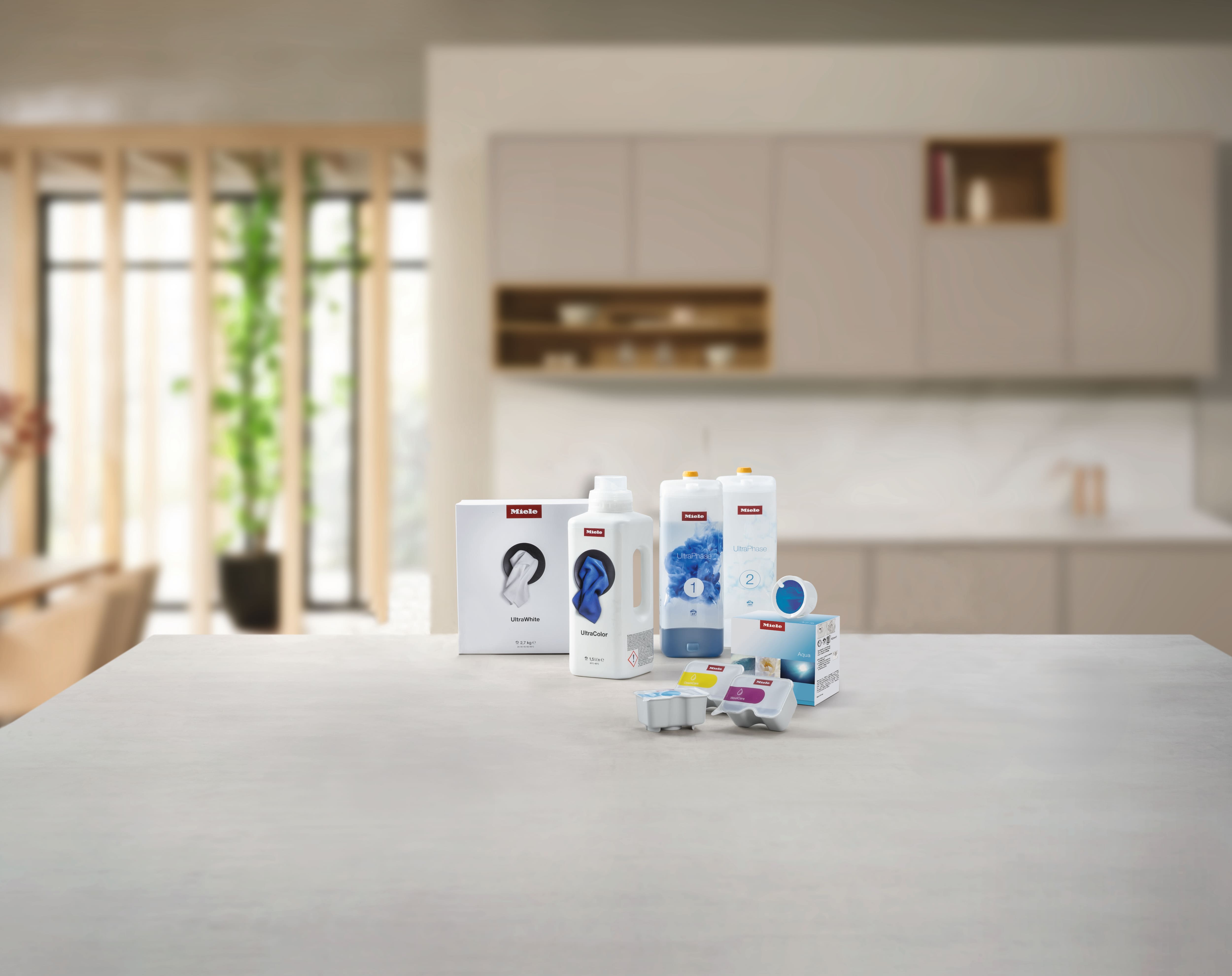 Assorted Miele laundry detergents and capsules on a kitchen counter, featuring UltraColor, UltraWhite, and TwinDos refills.