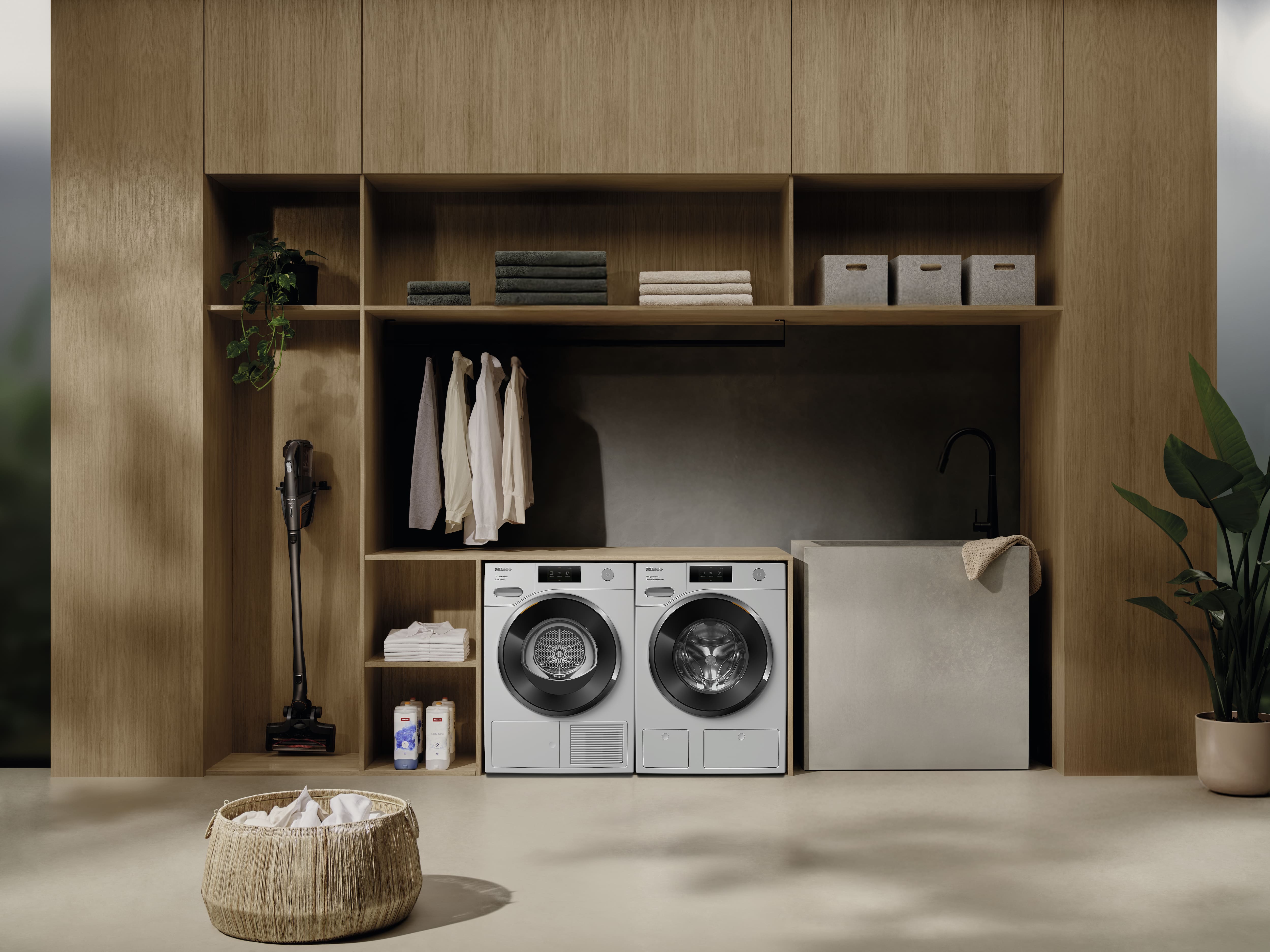 Modern laundry room featuring washer, dryer, sink, and open wood shelving, neatly organized for home care.