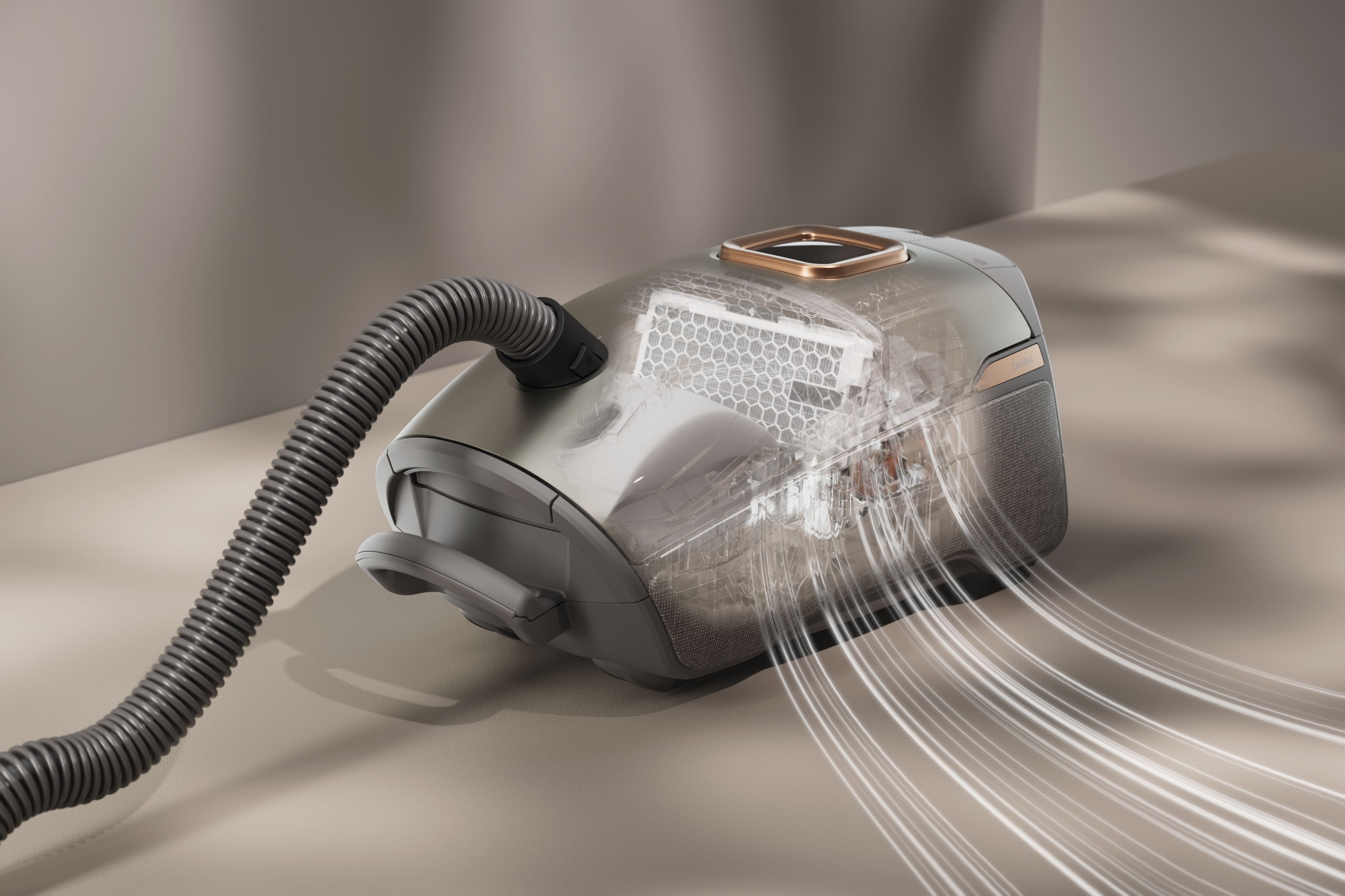 Aspirateur-traîneau au design épuré posé sur une table, dont le corps transparent laisse apparaître le filtre HEPA et les conduits d'air illustrant le parcours de l'aspiration. Aspirateur-traîneau au design épuré posé sur une table, dont le corps transparent laisse apparaître le filtre HEPA et les conduits d'air illustrant le parcours de l'aspiration.