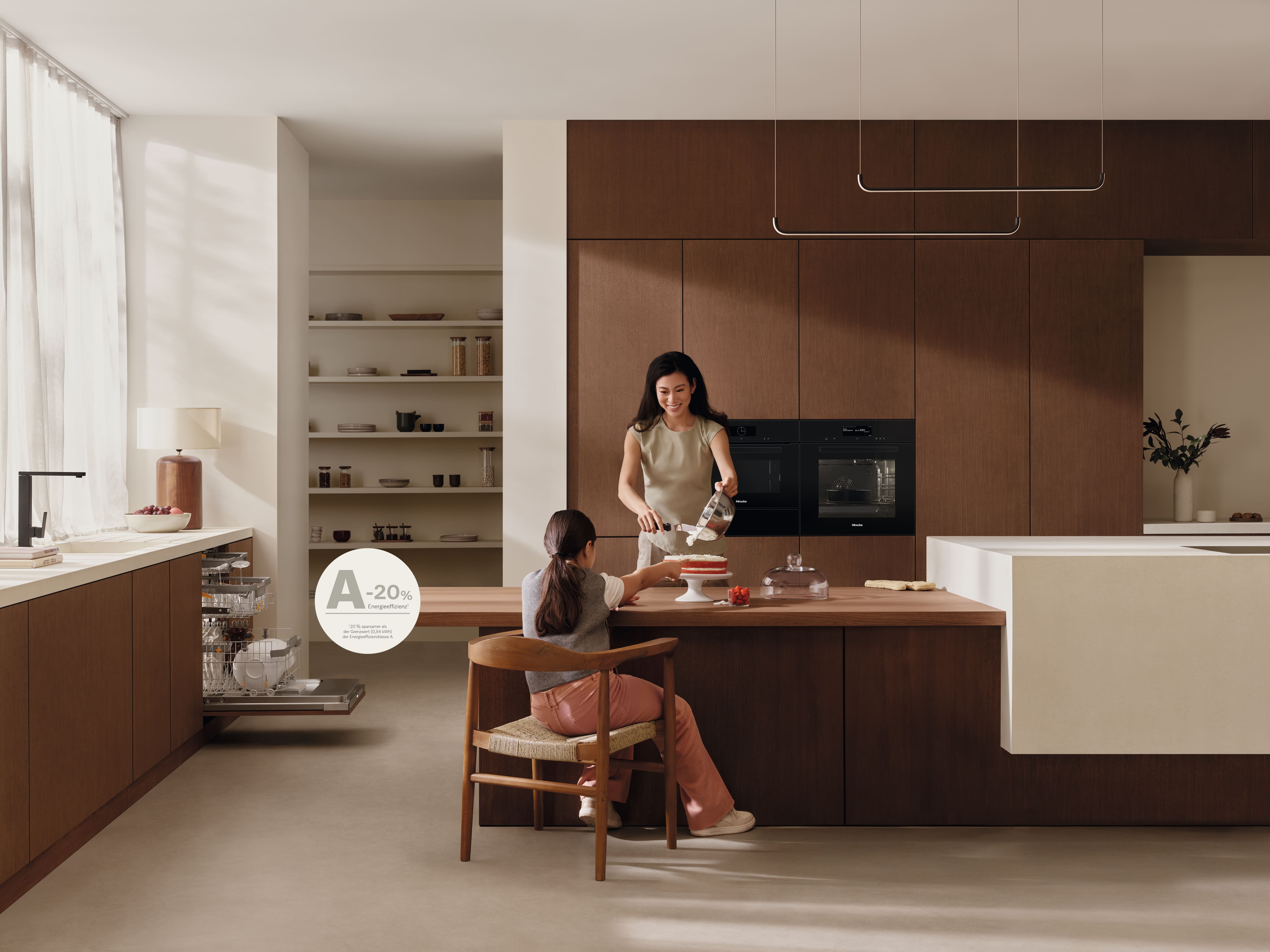 Moderne Küche mit Holzschränken; Erwachsener und Kind dekorieren einen Kuchen auf der Insel; energieeffiziente Geräte. Moderne Küche mit Holzschränken; Erwachsener und Kind dekorieren einen Kuchen auf der Insel; energieeffiziente Geräte.