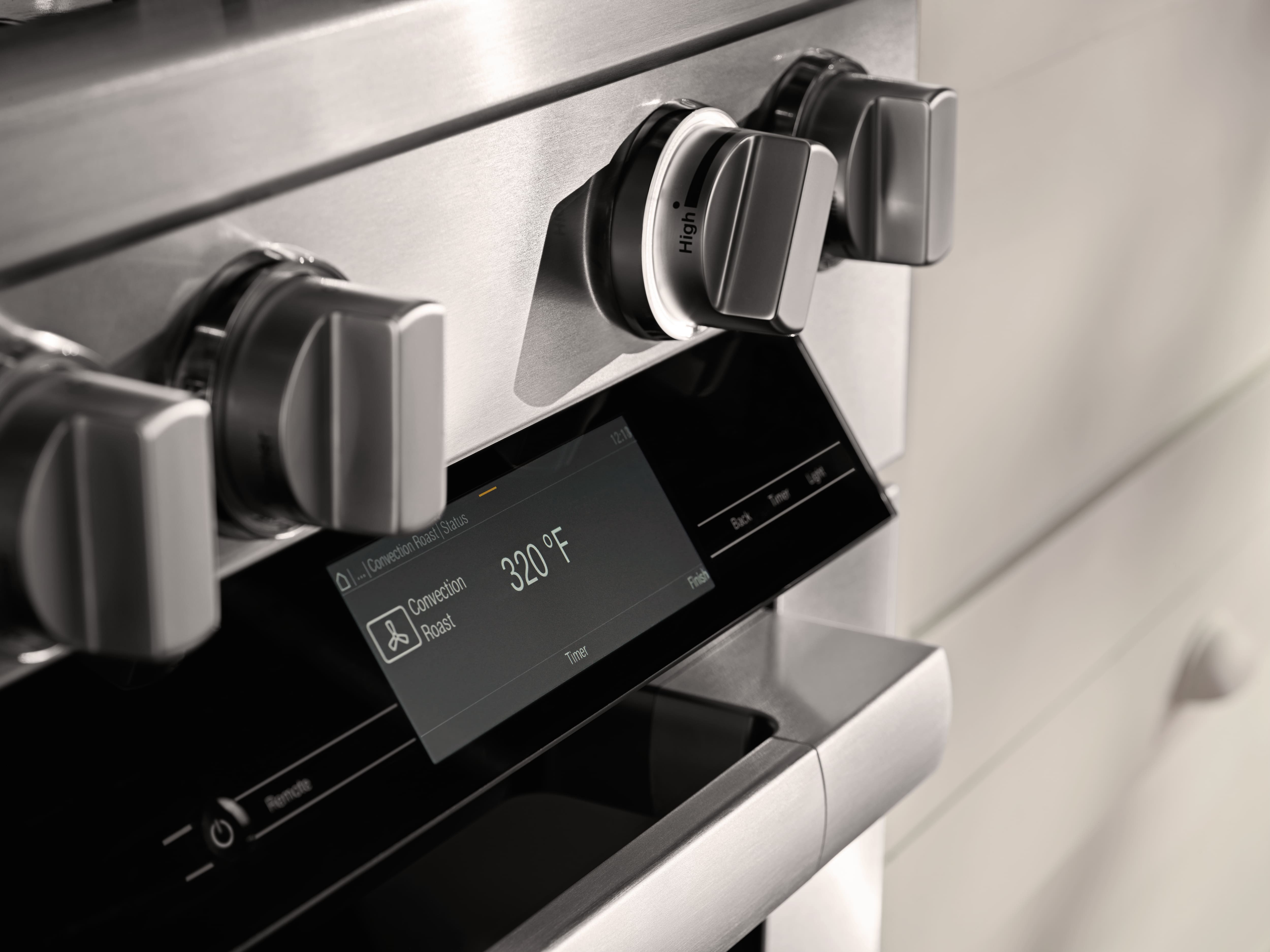 Close-up of a stainless steel oven control panel with burner knobs and a touchscreen set to Convection Roast at 320°F. Close-up of a stainless steel oven control panel with burner knobs and a touchscreen set to Convection Roast at 320°F.