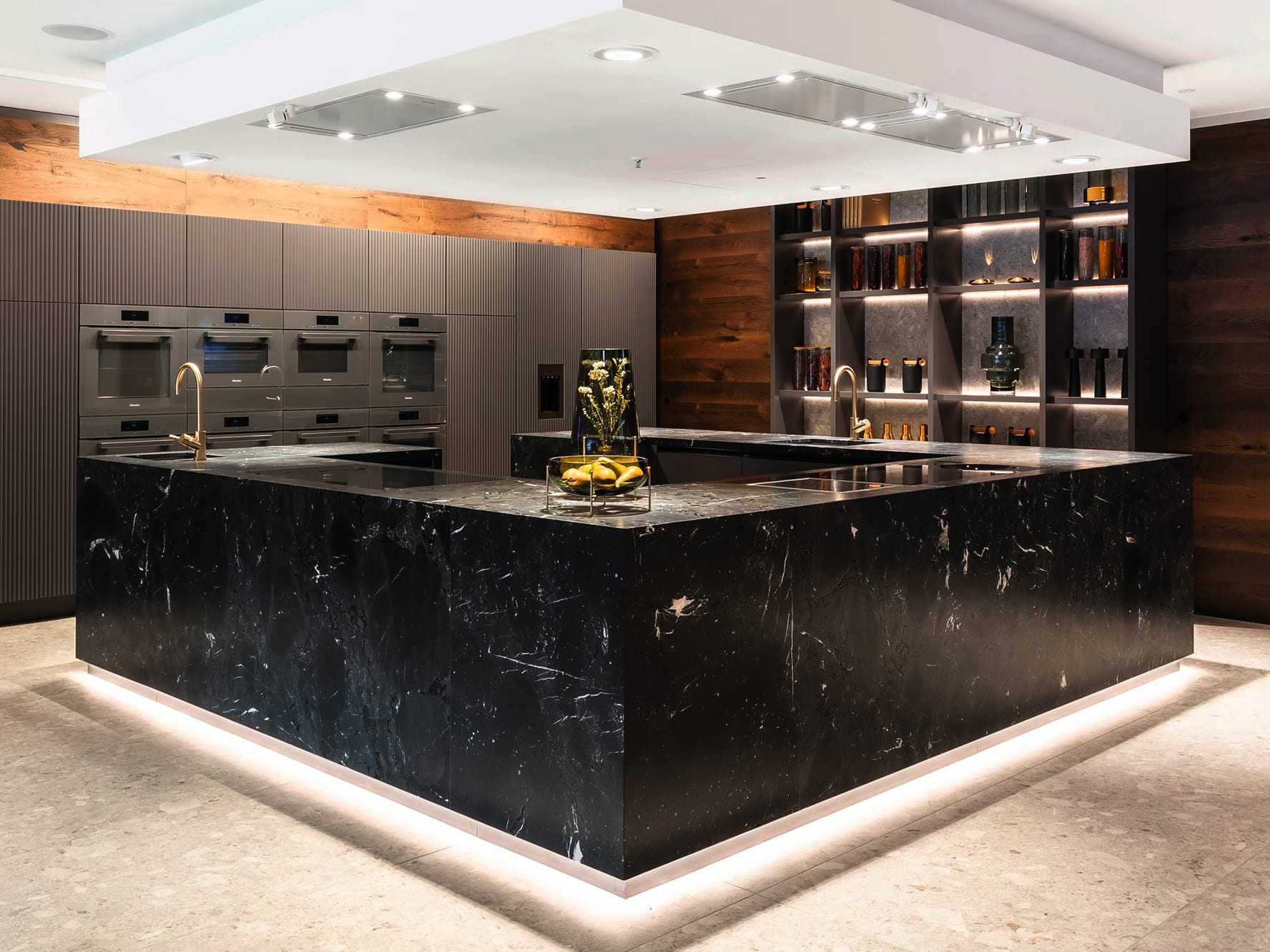 Moderne Designküche mit schwarzer Marmor-Kochinsel, Messingarmaturen, integrierten Backöfen und indirekt beleuchteten Holzregalen. Das elegante Ambiente verbindet hochwertige Materialien mit zeitgemäßem Küchendesign. Moderne Designküche mit schwarzer Marmor-Kochinsel, Messingarmaturen, integrierten Backöfen und indirekt beleuchteten Holzregalen. Das elegante Ambiente verbindet hochwertige Materialien mit zeitgemäßem Küchendesign.