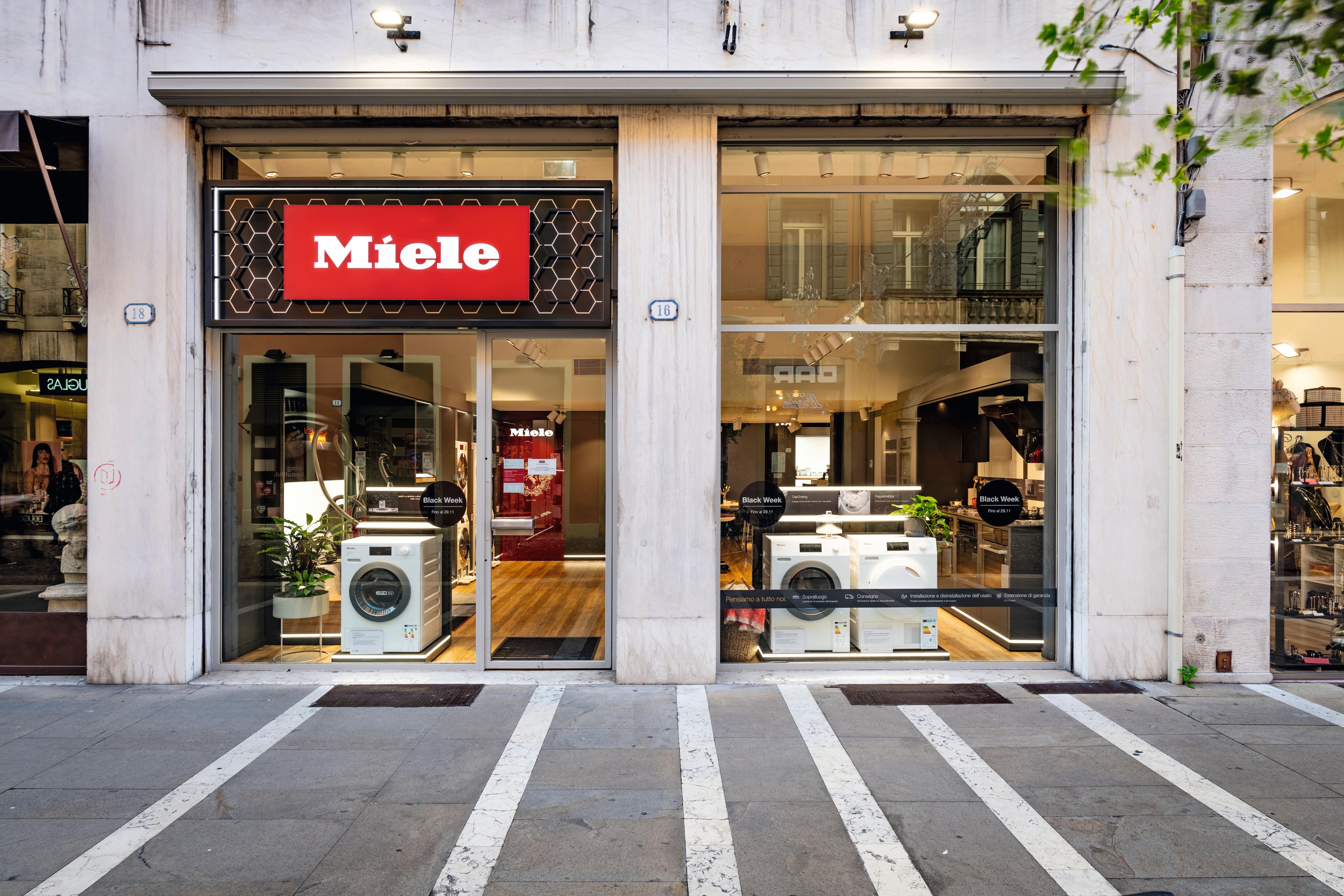 Vista a livello strada di un negozio Miele con lavatrici in vetrina e promozioni Black Week. Vista a livello strada di un negozio Miele con lavatrici in vetrina e promozioni Black Week.
