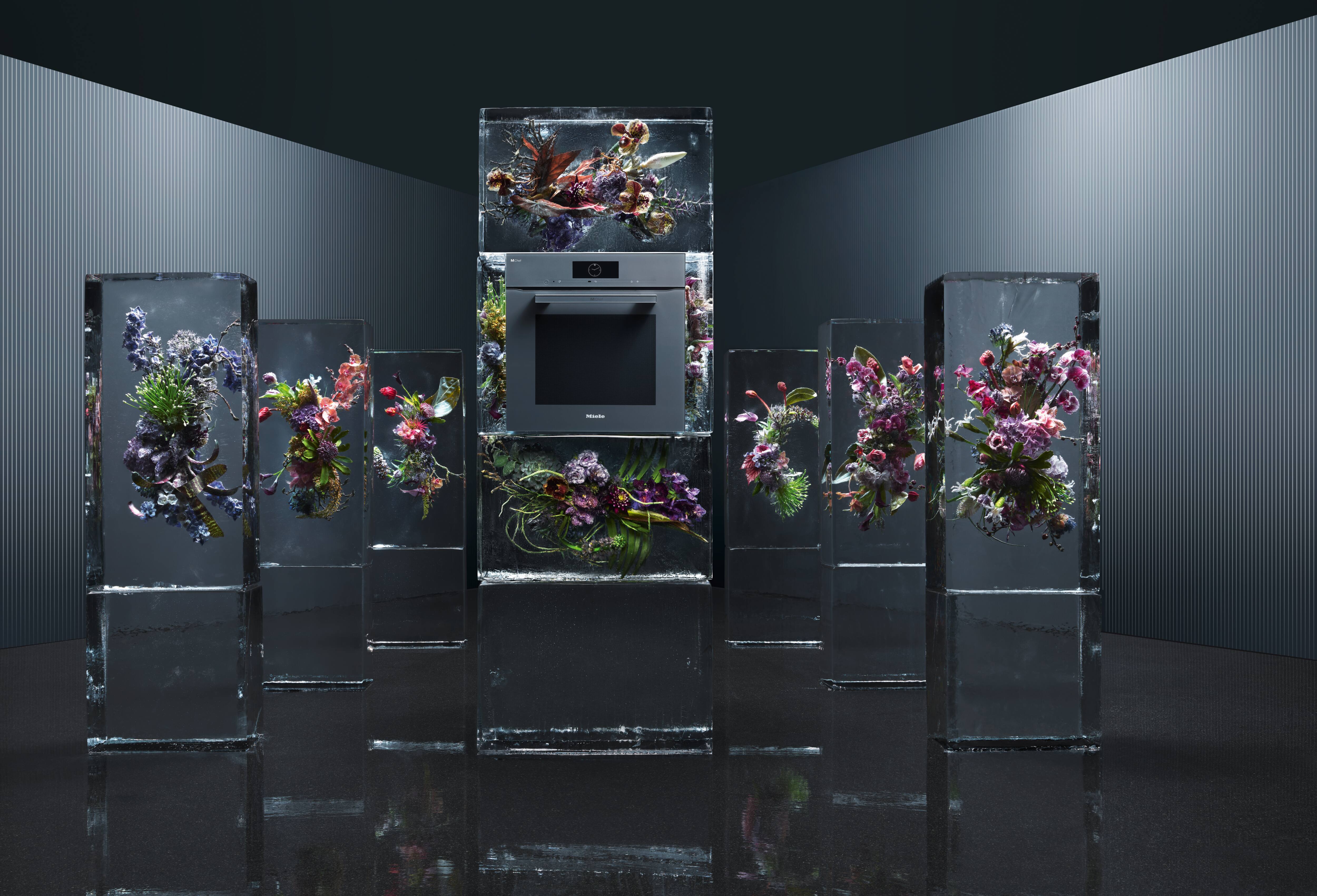 Miele built-in oven displayed amid tall, ice-like glass pillars encasing colorful floral arrangements. Miele built-in oven displayed amid tall, ice-like glass pillars encasing colorful floral arrangements.