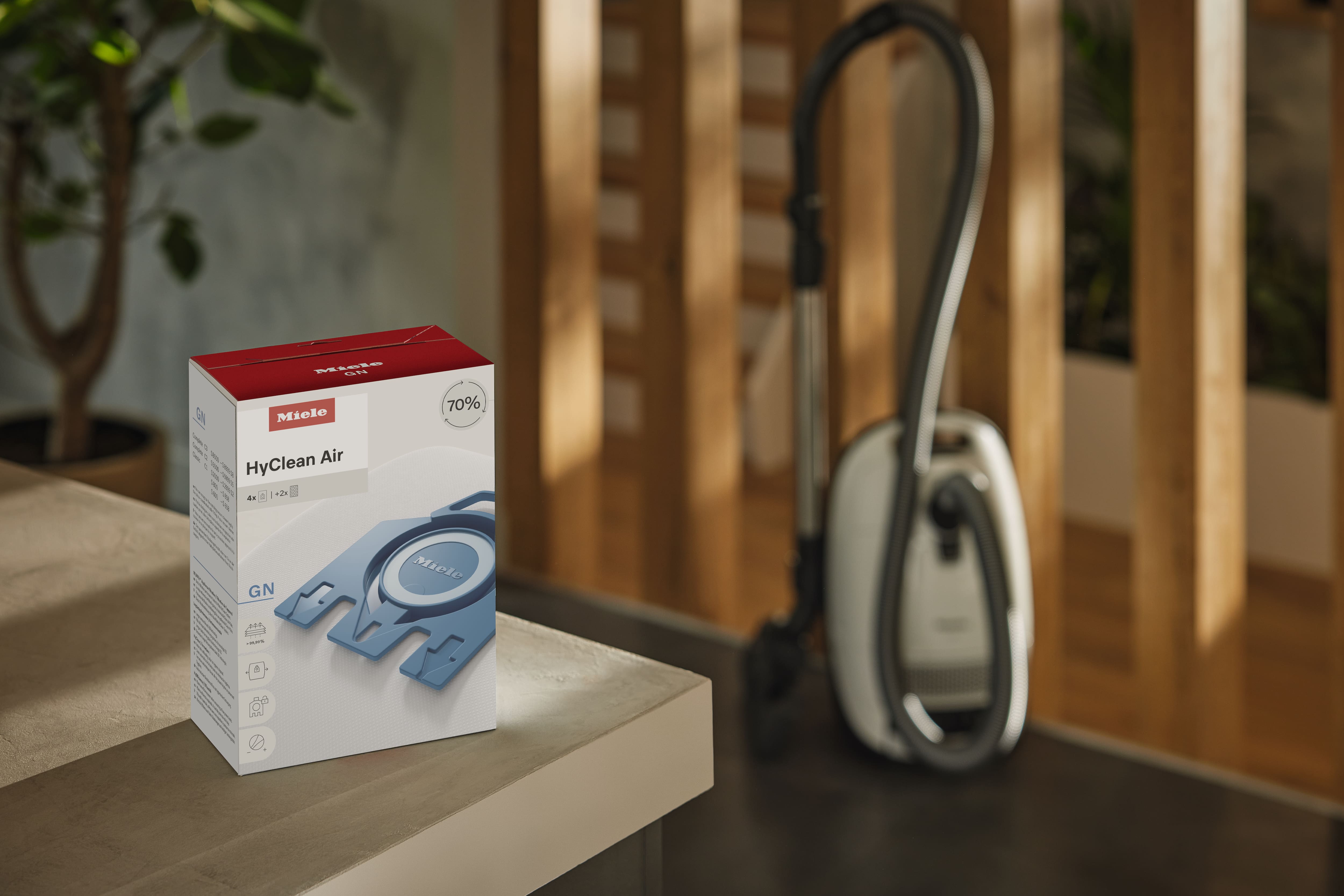 Box of Miele HyClean Air GN vacuum bags on a countertop with a canister vacuum cleaner in the background indoors. Box of Miele HyClean Air GN vacuum bags on a countertop with a canister vacuum cleaner in the background indoors.