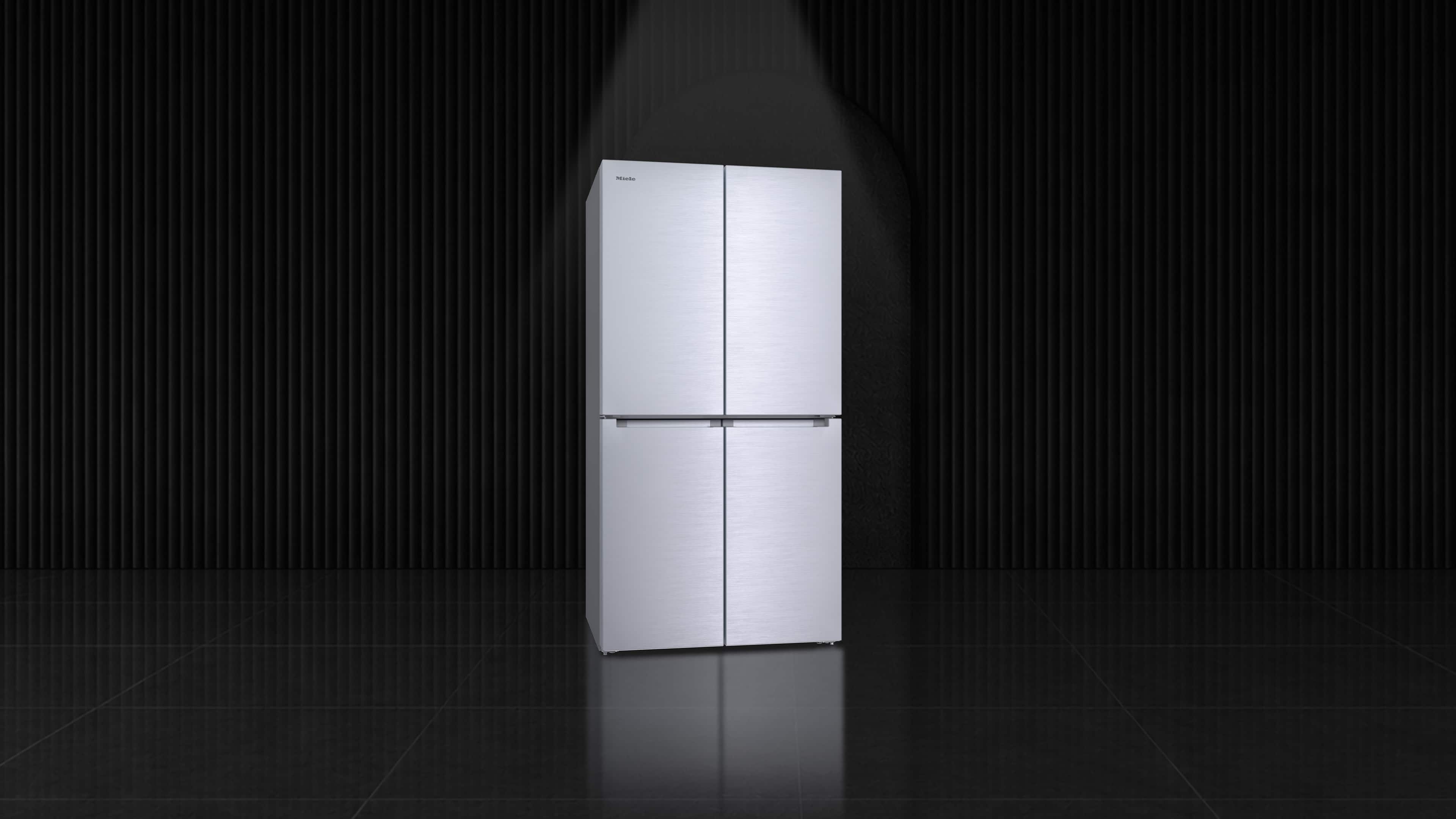 Sleek stainless steel four‑door refrigerator showcased under a spotlight against a dark, modern ribbed wall. Sleek stainless steel four‑door refrigerator showcased under a spotlight against a dark, modern ribbed wall.