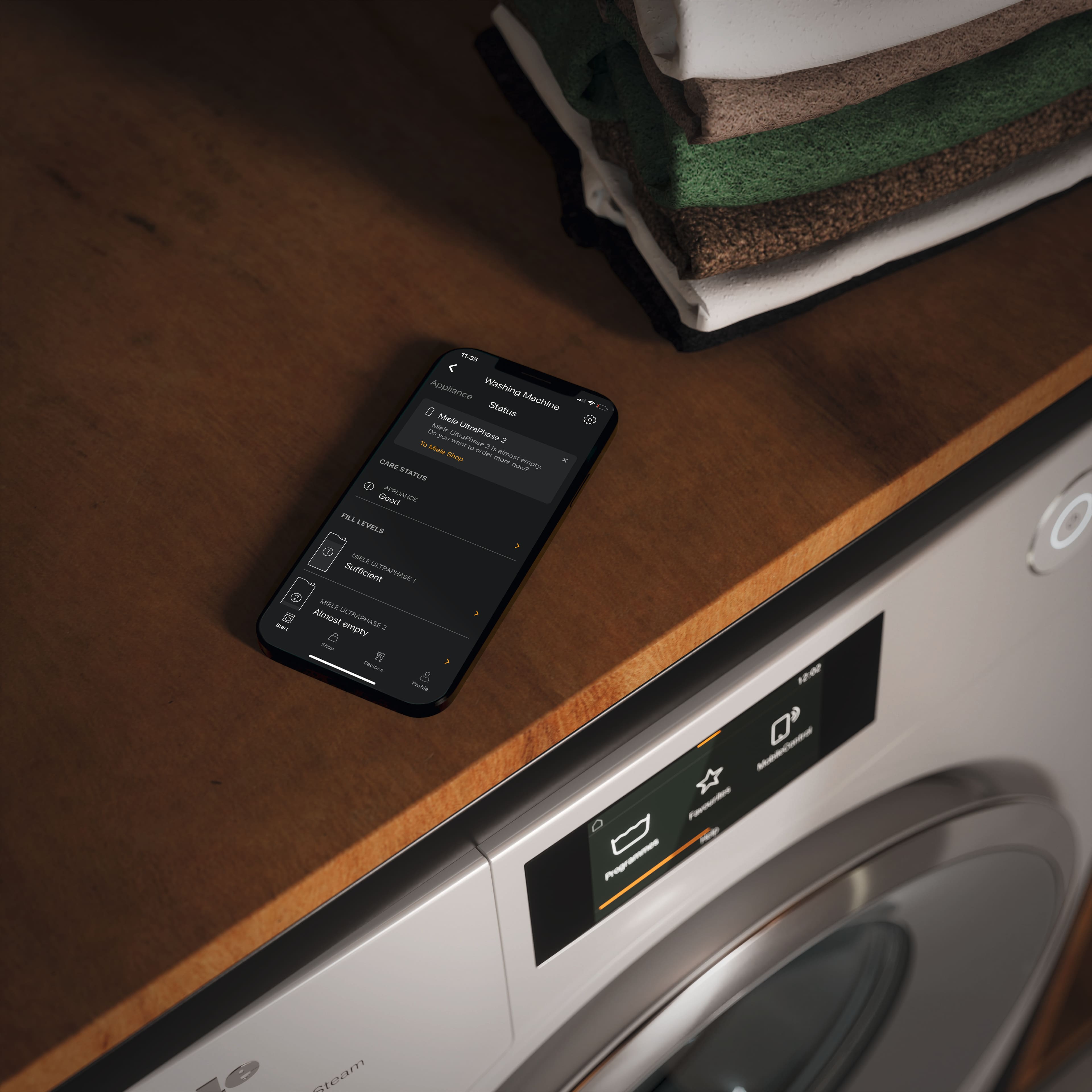 Mobile phone showing Miele App on top of a table with washing machine underneath