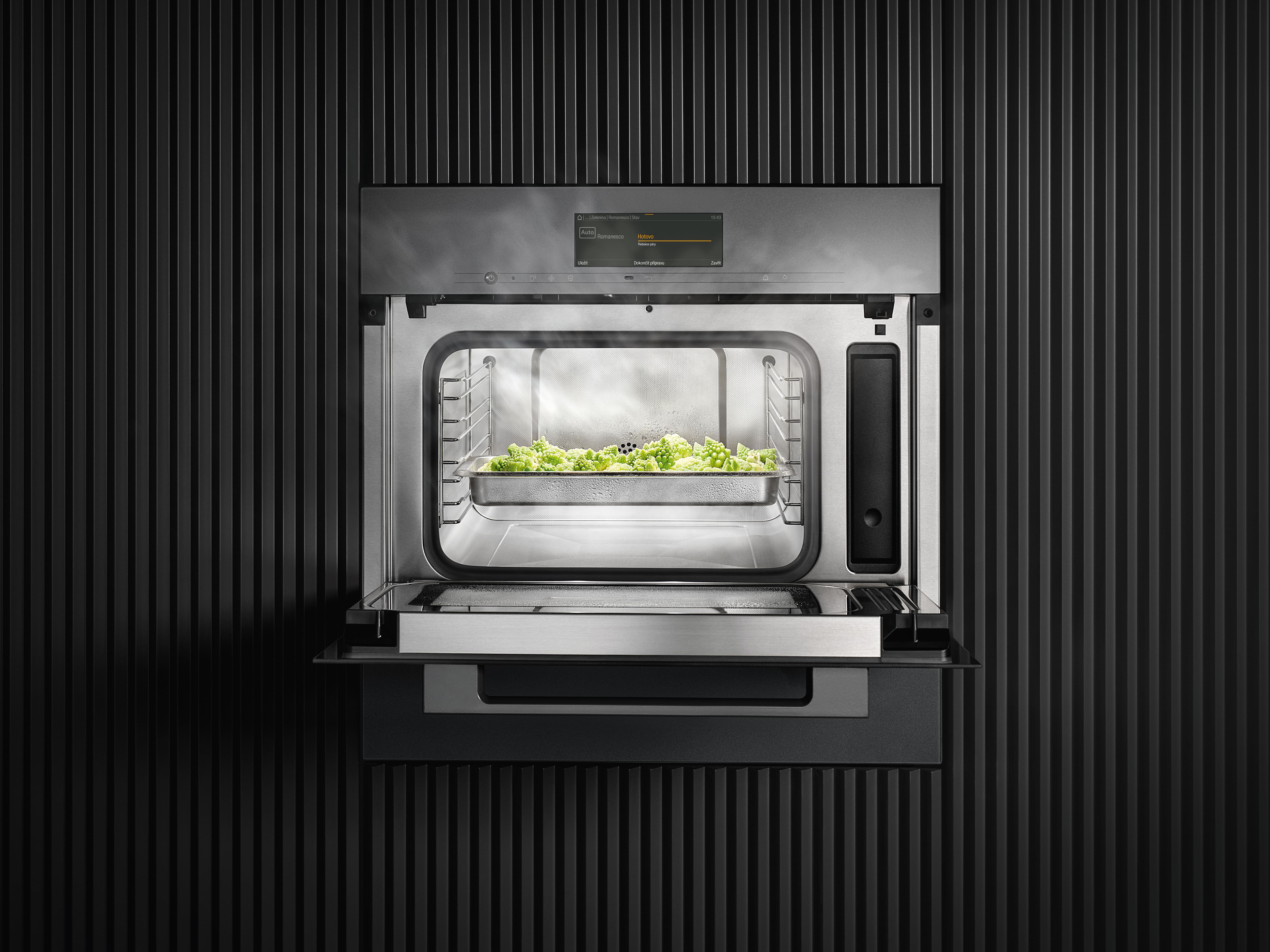 A close-up of an open steam oven shows food cooking with evenly distributed steam inside. A close-up of an open steam oven shows food cooking with evenly distributed steam inside.