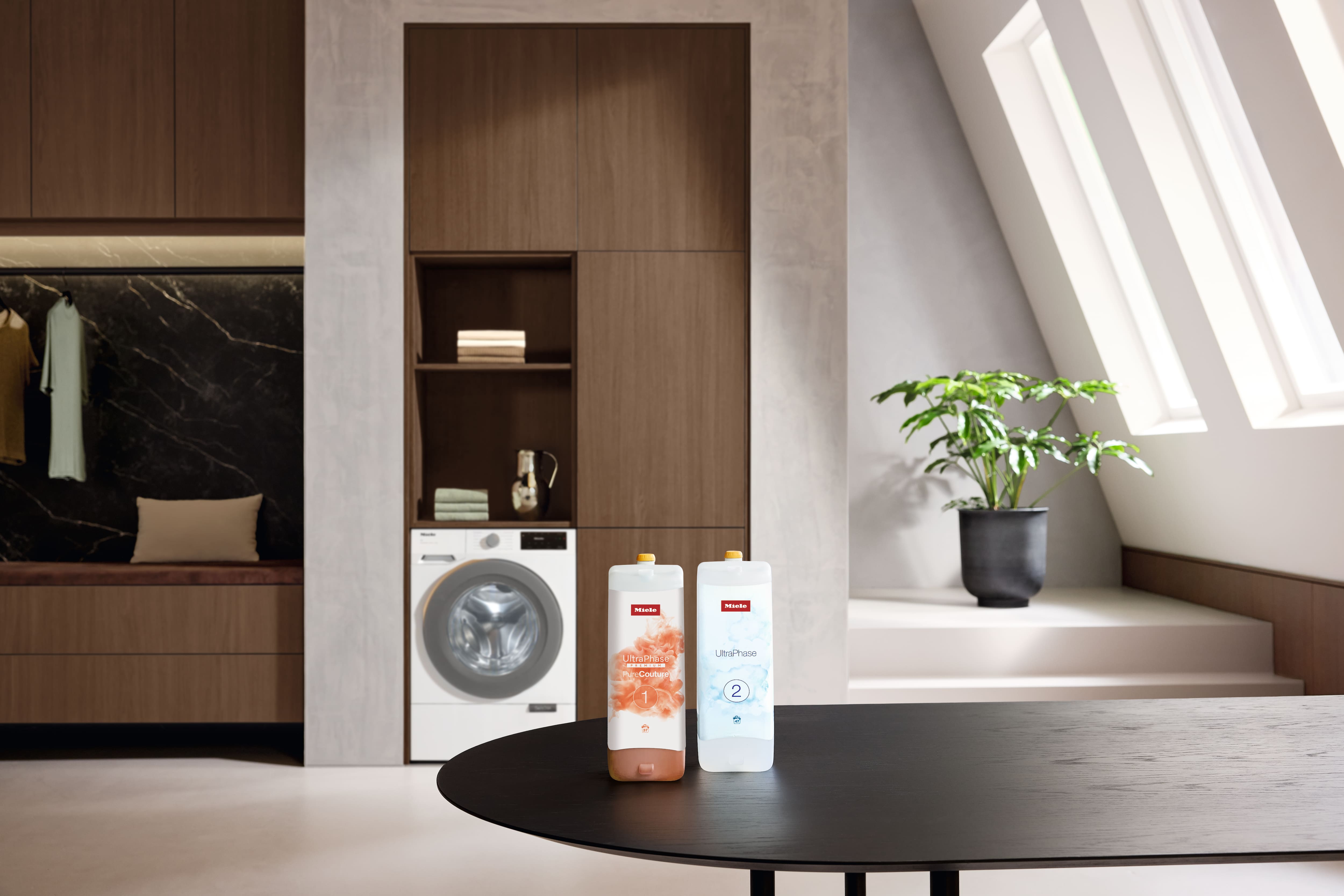 Moderner Waschraum mit einem Frontlader und zwei Miele UltraPhase Waschmitteln auf einem Tisch. Moderner Waschraum mit einem Frontlader und zwei Miele UltraPhase Waschmitteln auf einem Tisch.