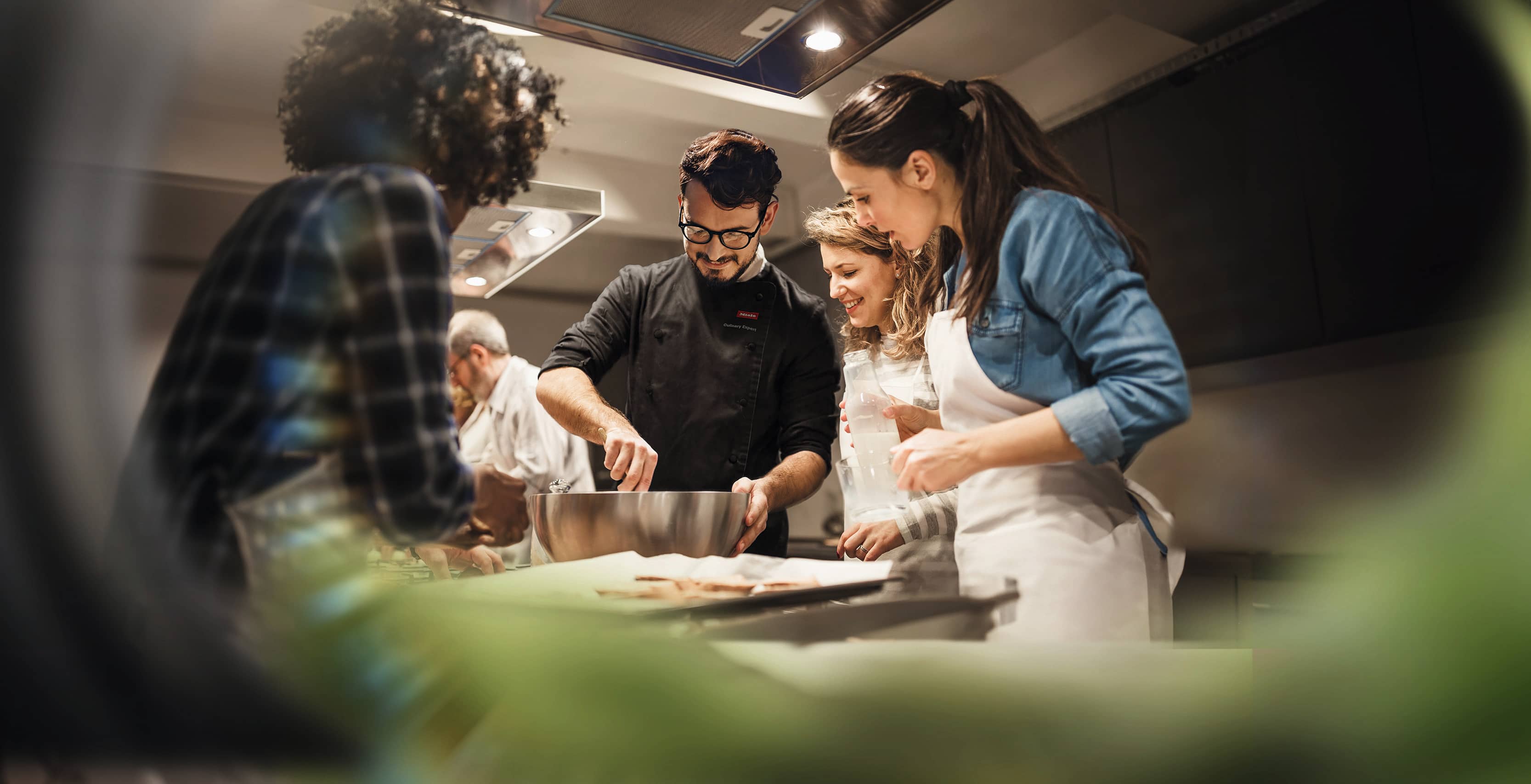 chef con attorno persone che imparano a cucinare