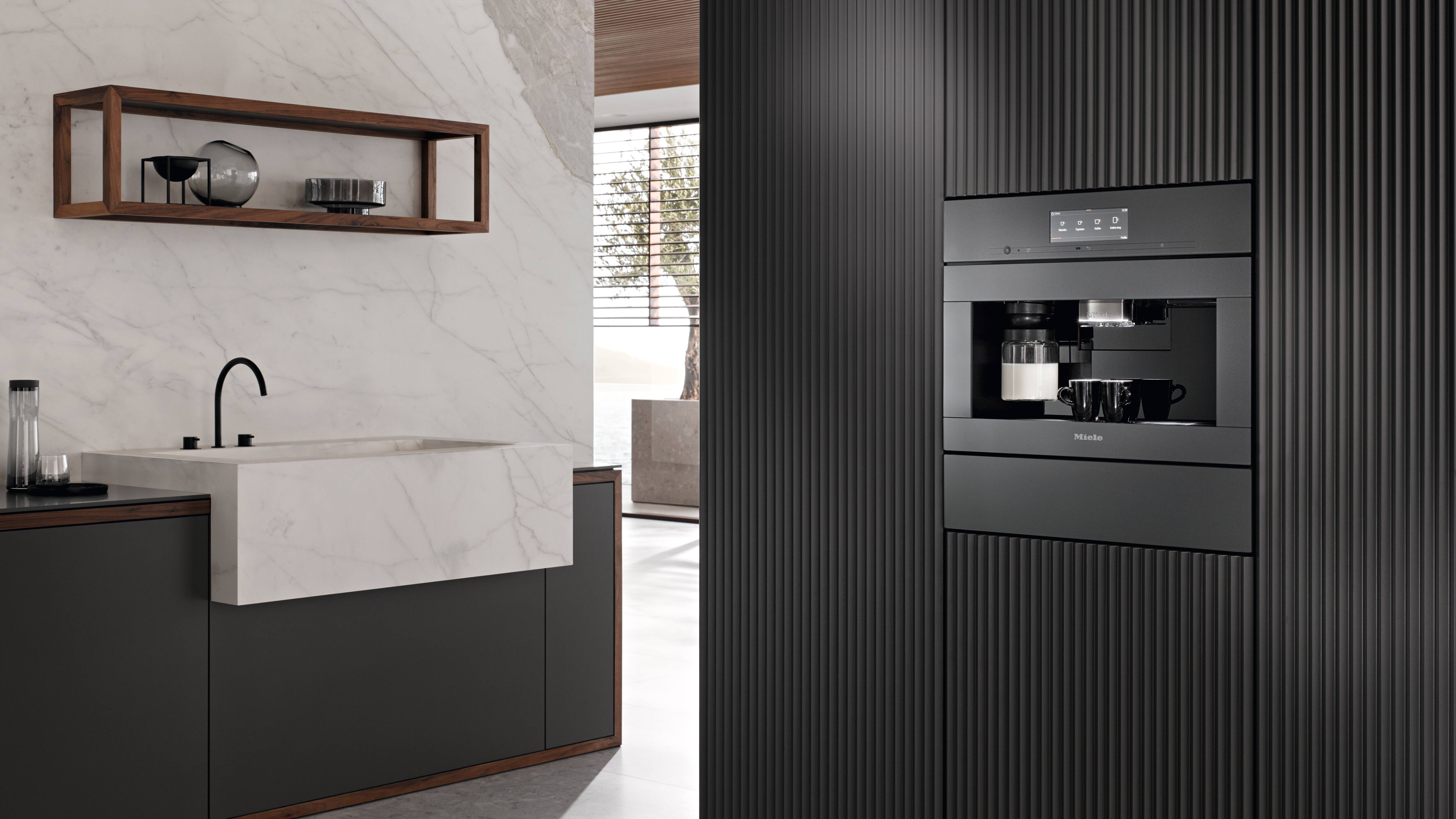 Sleek modern kitchen with built-in espresso machine and marble sink; separate wooden wall shelf with minimalist decor.