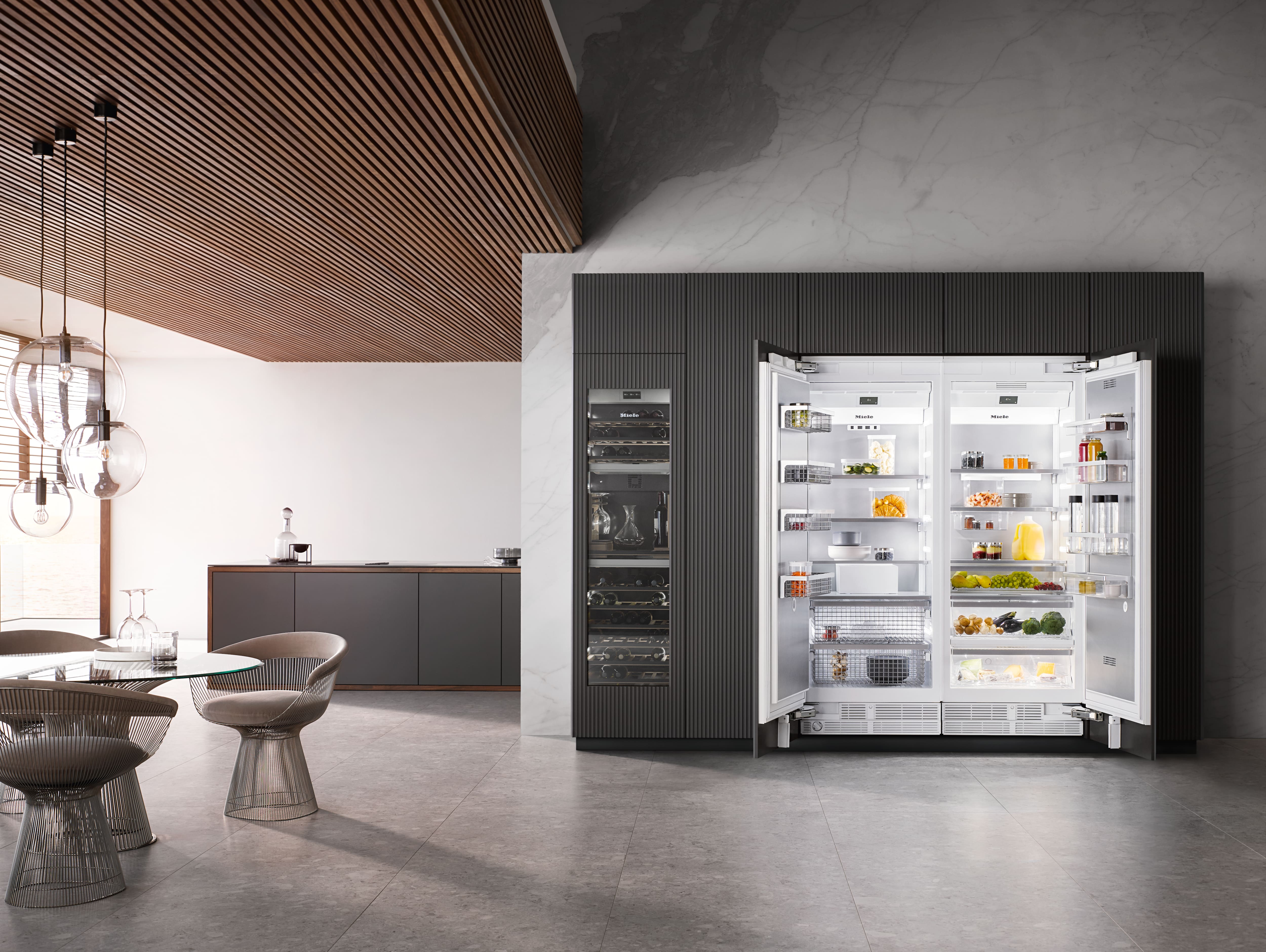 Cocina moderna con refrigerador de dos-puertas empotrado y abierto, que exhibe alimentos organizados; con gabinetes y lámparas colgantes decorativas. Cocina moderna con refrigerador de dos-puertas empotrado y abierto, que exhibe alimentos organizados; con gabinetes y lámparas colgantes decorativas.