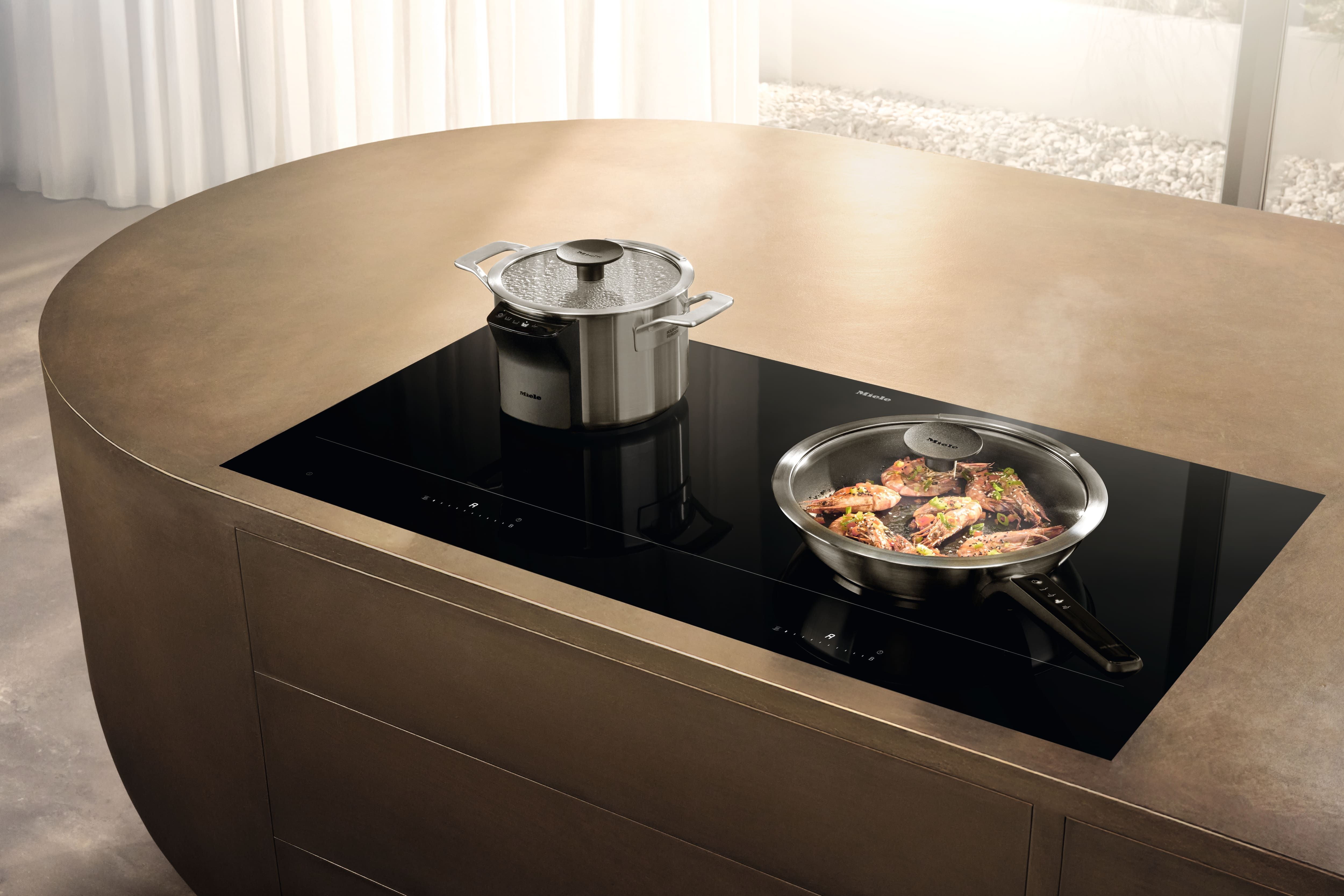 Sleek kitchen island with black induction cooktop; pot steaming and pan sautéing prawns under a lid, modern ambiance. Sleek kitchen island with black induction cooktop; pot steaming and pan sautéing prawns under a lid, modern ambiance.