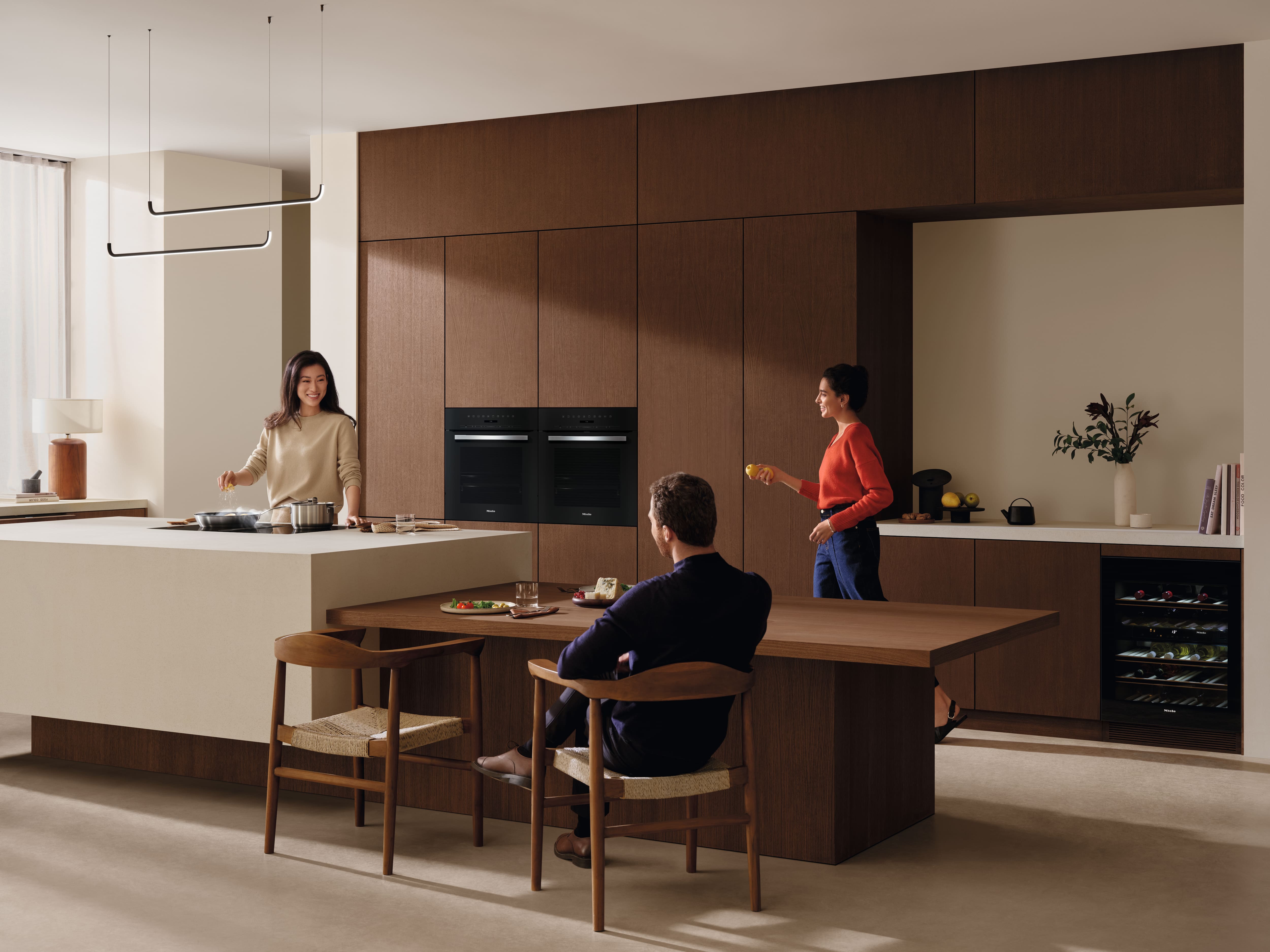 Contemporary kitchen with wood cabinets and island, featuring built-in black wall ovens; product detail shown.