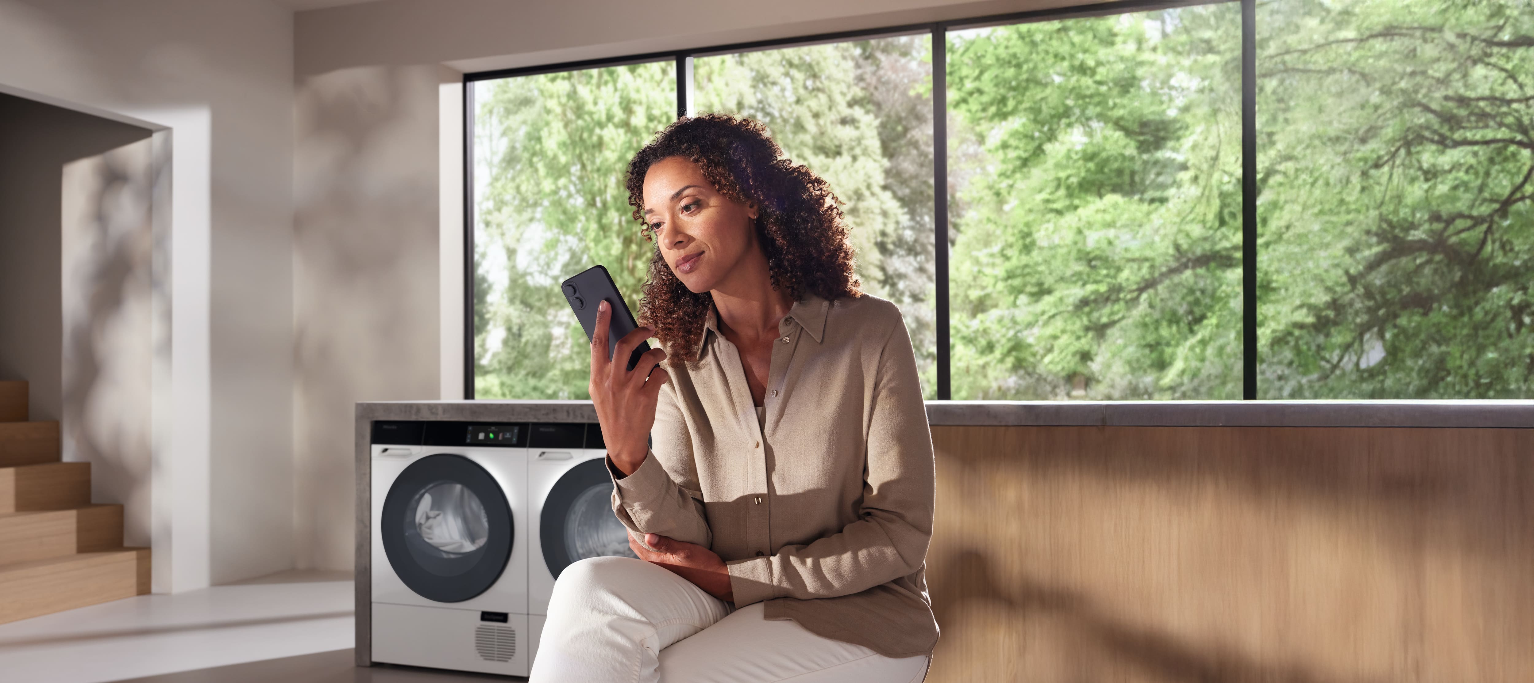 Eine Frau, die auf ihrem Smartphone die Details ihres Miele Geräts überprüft