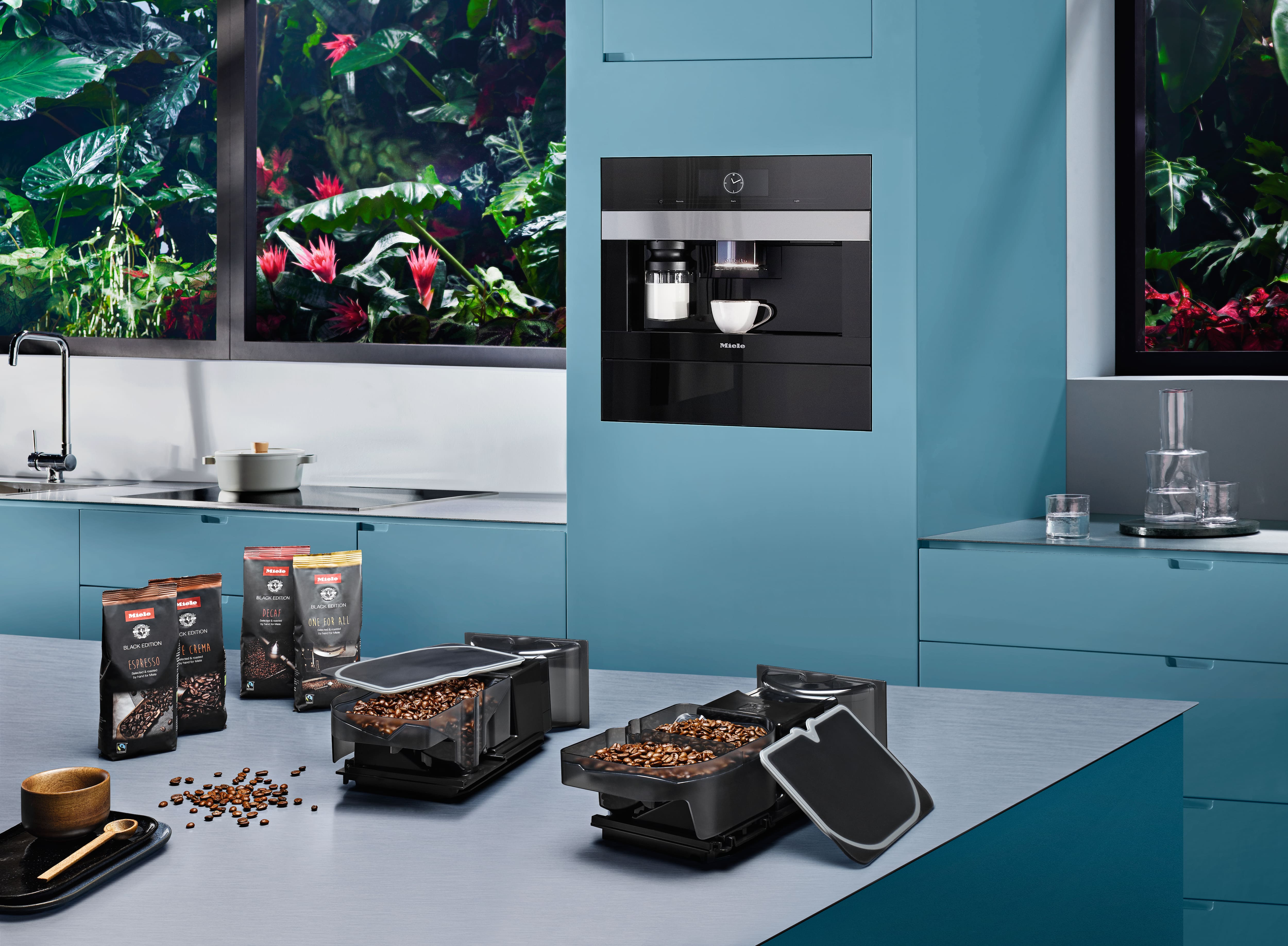 Modern blue kitchen with built-in Miele coffee machine and bean containers on counter, promoting coffee setup. Modern blue kitchen with built-in Miele coffee machine and bean containers on counter, promoting coffee setup.