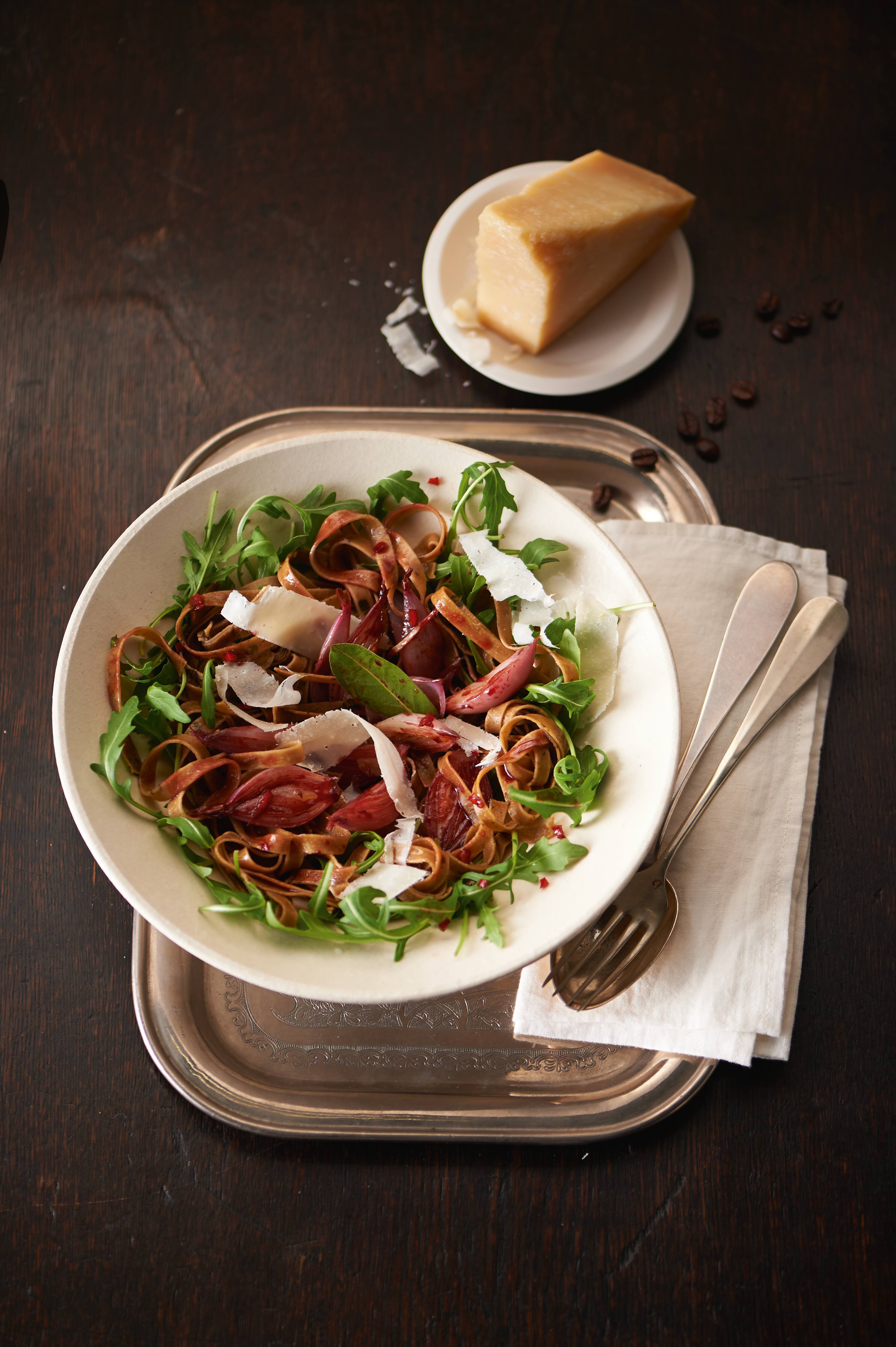 Rustic bowl of tagliatelle with arugula, roasted shallots, and shaved Parmesan; served on a tray with cheese wedge. Rustic bowl of tagliatelle with arugula, roasted shallots, and shaved Parmesan; served on a tray with cheese wedge.