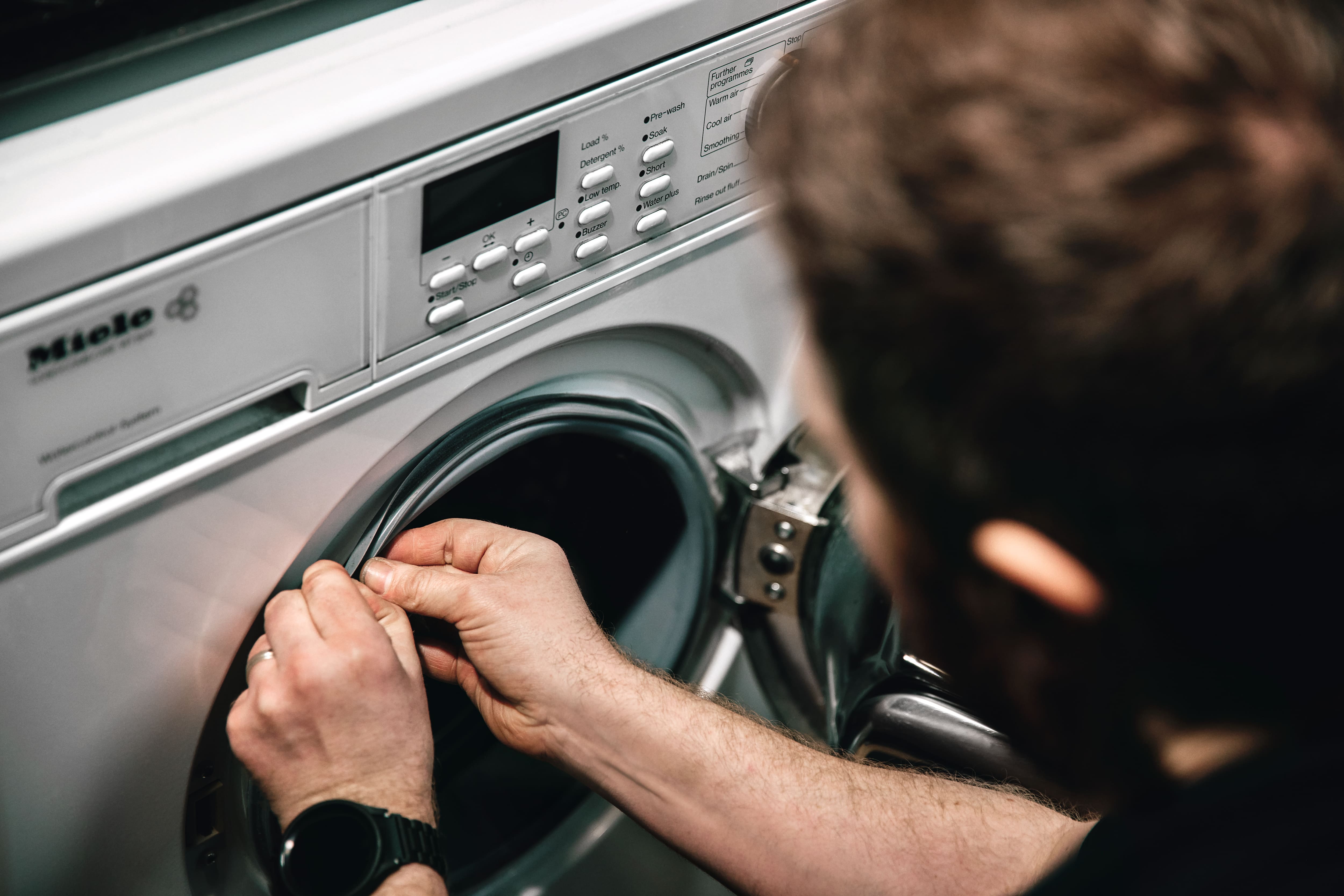 Miele technician maintaining washing machine Miele technician maintaining washing machine