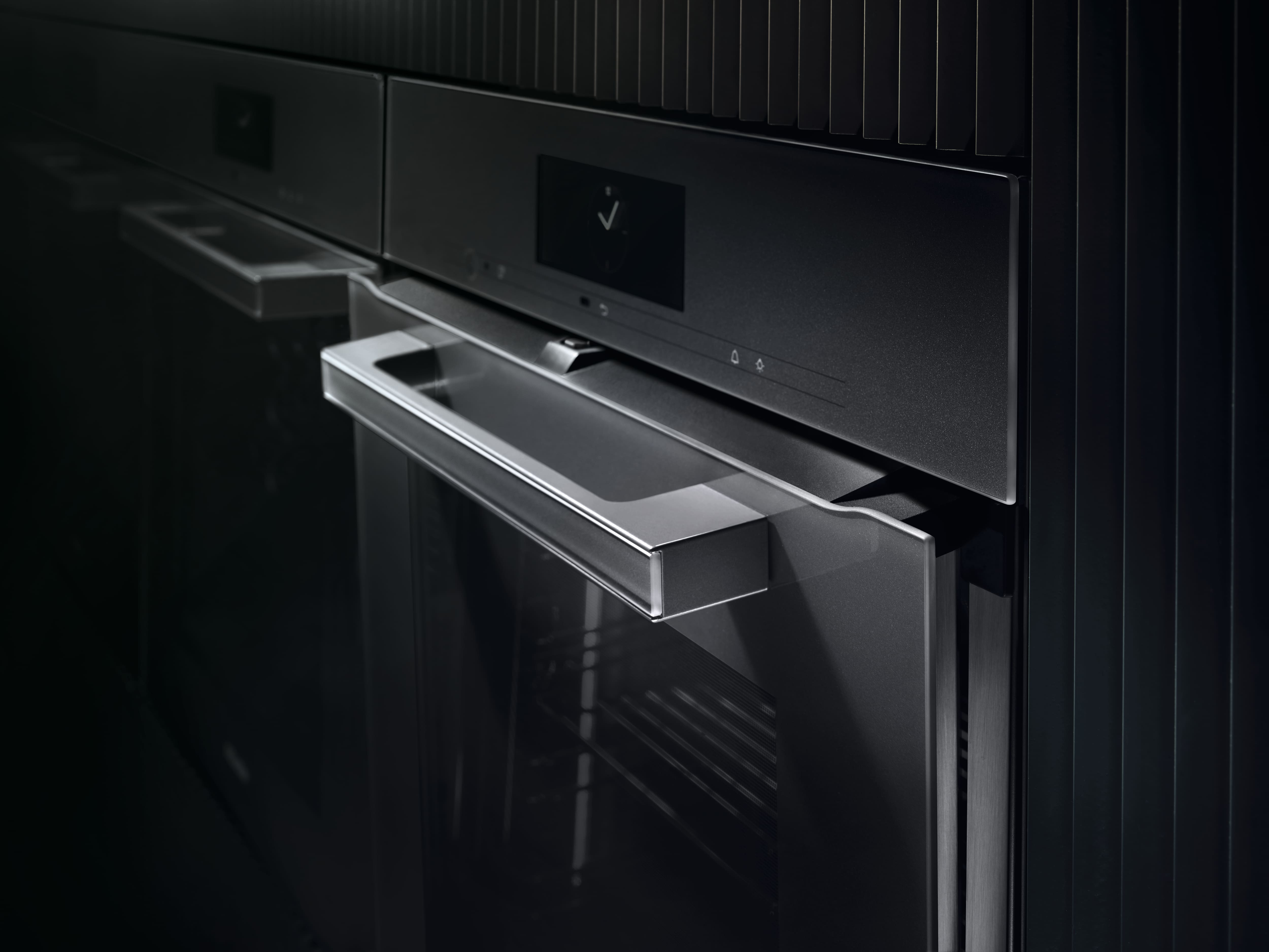 Close-up visuals of a modern black built-in oven, highlighting its glass door, angular metal handle, and touch display. Close-up visuals of a modern black built-in oven, highlighting its glass door, angular metal handle, and touch display.