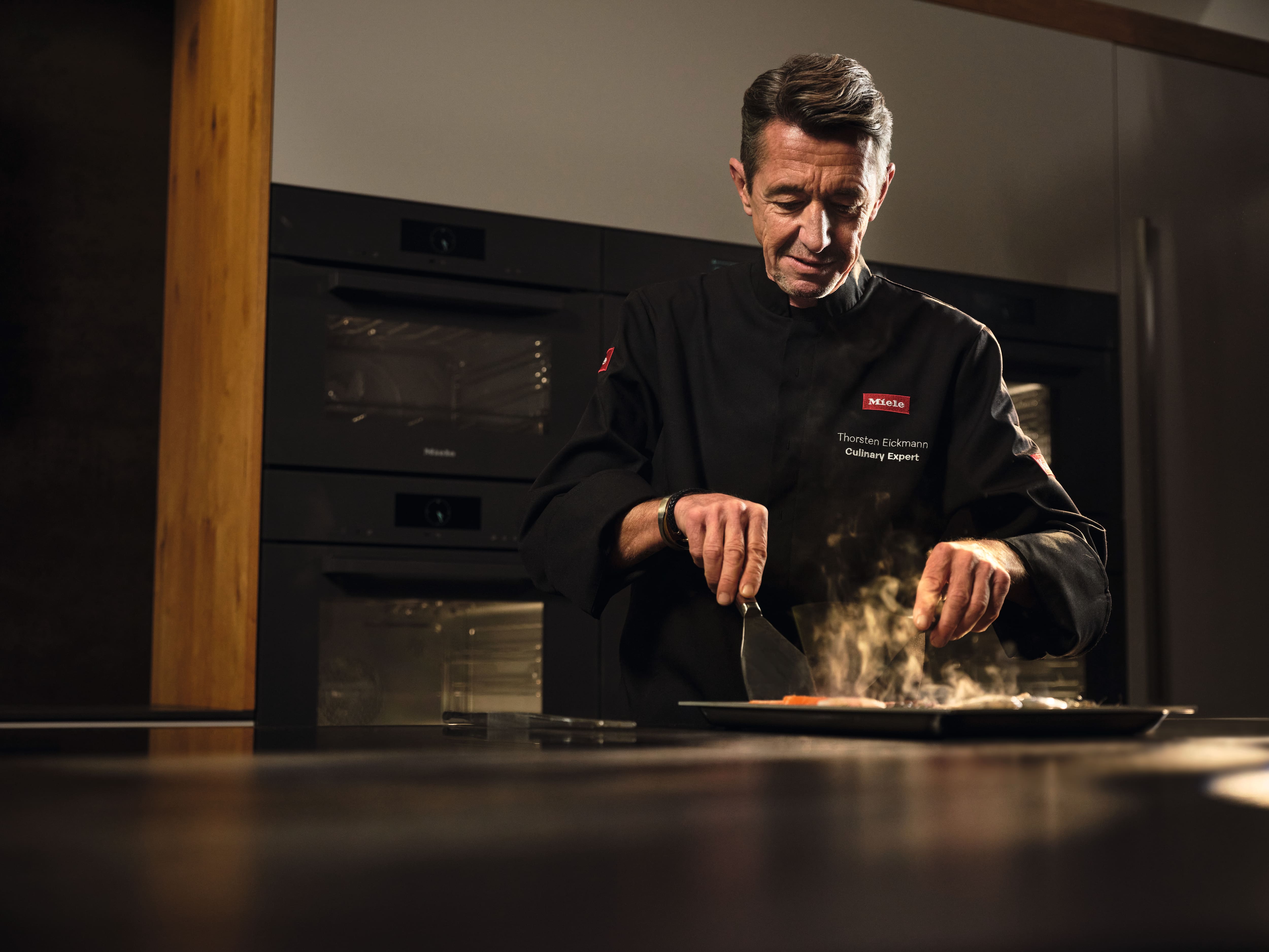 Szef kuchni przygotowujący owoce morza na płycie Miele Szef kuchni przygotowujący owoce morza na płycie Miele