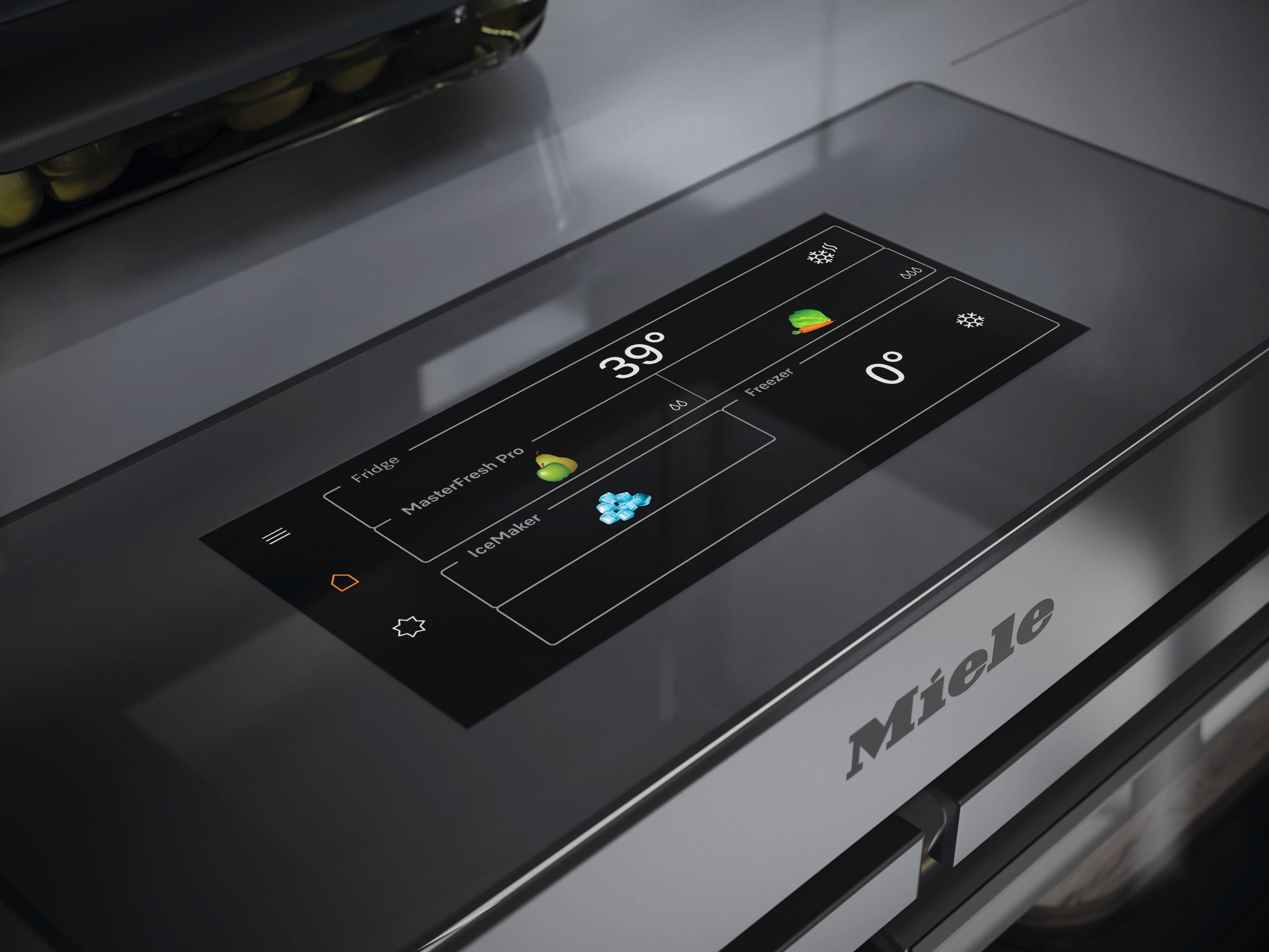 Close-up do painel de controle com tela sensível ao toque de uma geladeira Miele sobre uma superfície de aço inoxidável, mostrando as temperaturas de 39° para o compartimento de refrigeração e 0° para o congelador, indicadas por ícones. Close-up do painel de controle com tela sensível ao toque de uma geladeira Miele sobre uma superfície de aço inoxidável, mostrando as temperaturas de 39° para o compartimento de refrigeração e 0° para o congelador, indicadas por ícones.