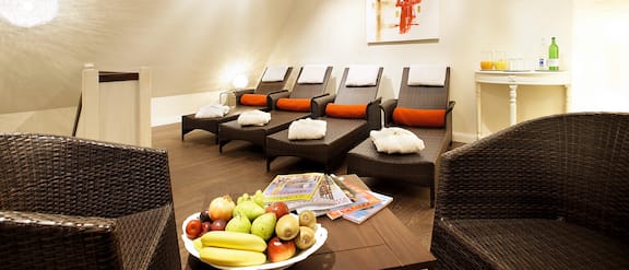 Area wellness con lettini, sedie e cesti di frutta.